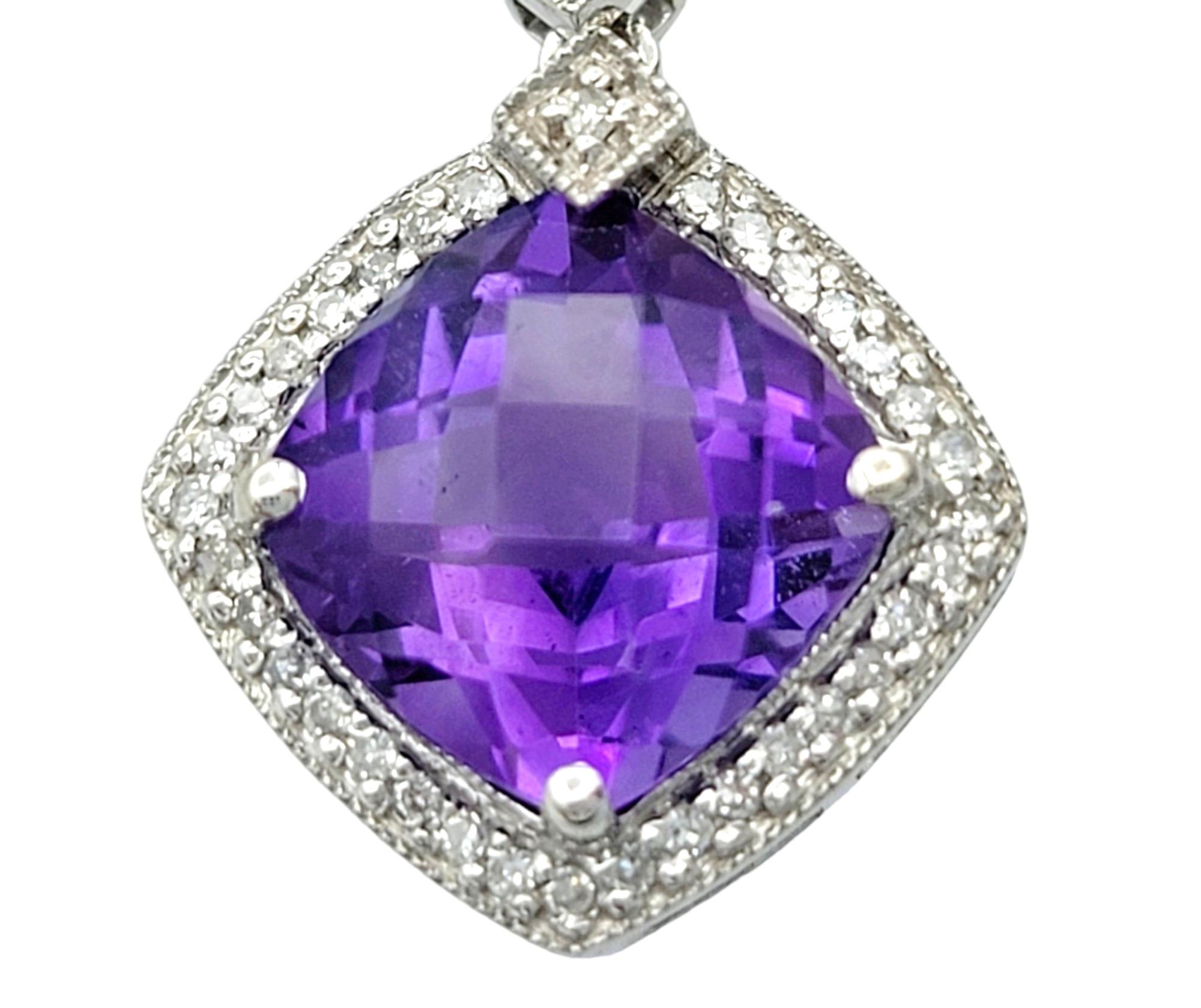 These gorgeous earrings, set in elegant 14 karat white gold, showcase a sophisticated and harmonious design. The central feature in each earring is a cushion-cut amethyst, exuding a rich purple hue. Surrounding the amethyst is a sparkling halo of