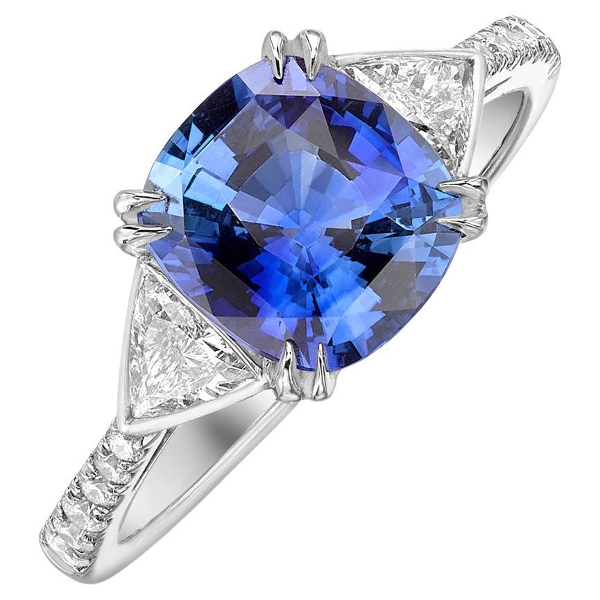 A stunning cushion cut blue sapphire and trillion cut diamond 3 stone ring with a microset diamond shank.  The centre stone is claw set with rubover set trillion cut diamonds, the ring is platinum, hallmarked at the London Assay Office.  Cushion cut