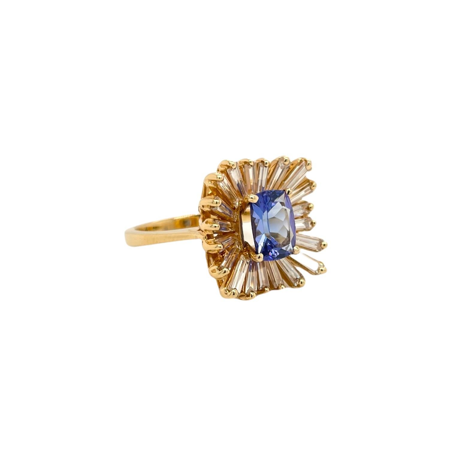 Fancy tanzanite and diamond baguette ballerina style ring in 18k yellow gold. Ring contains one 8x6mm cushion cut tanzanite, 1.31ct accented by a cluster of flowing baguette cut diamonds, totaling 1.48tcw. Diamonds are G-H in color and SI1 in