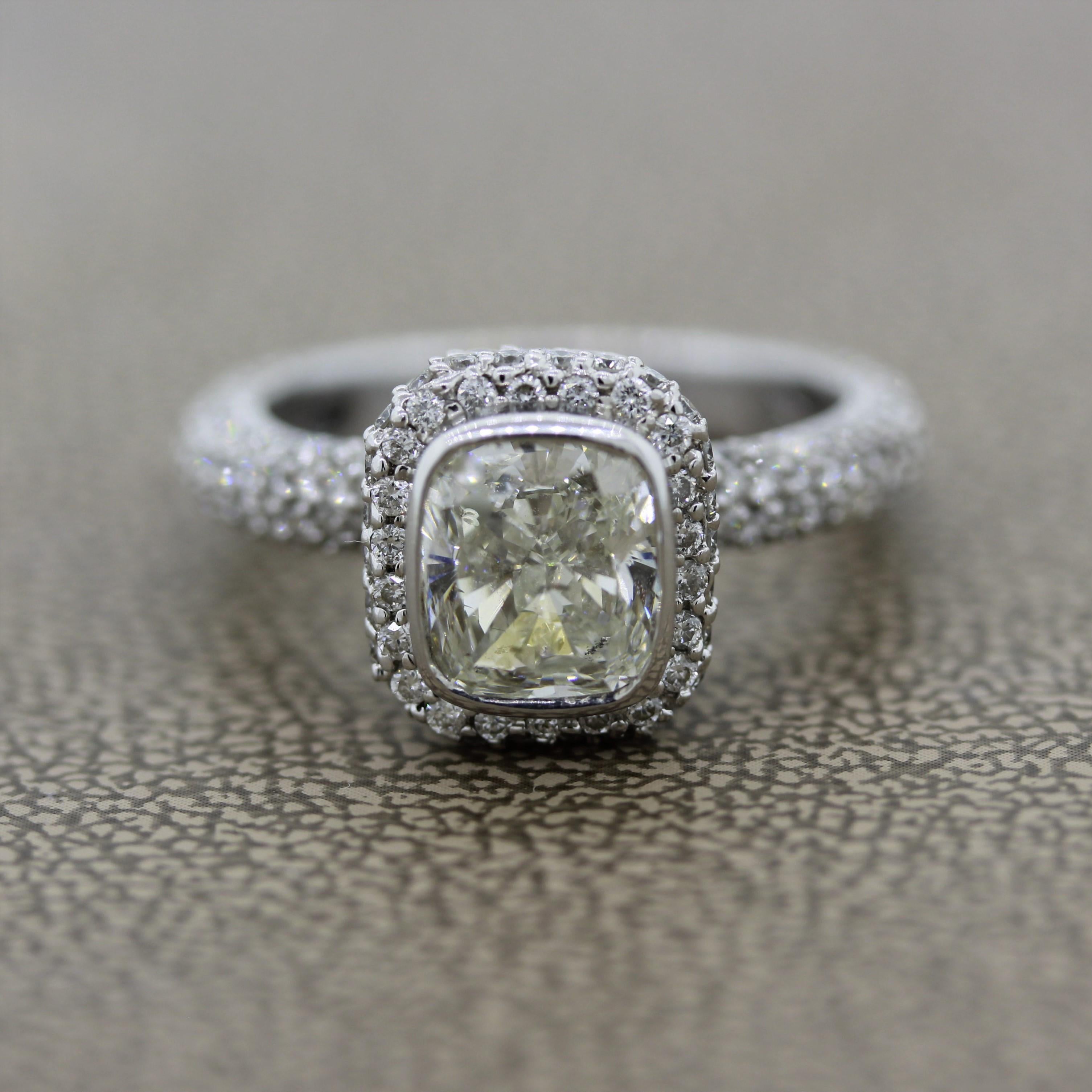 A lovely engagement ring meant to last many lifetimes! It features a 1.50 carat cushion cut diamond which is bezel set in the center. It is accented by 1.19 carats of round brilliant cut diamonds set around the center stone as well as the sides of