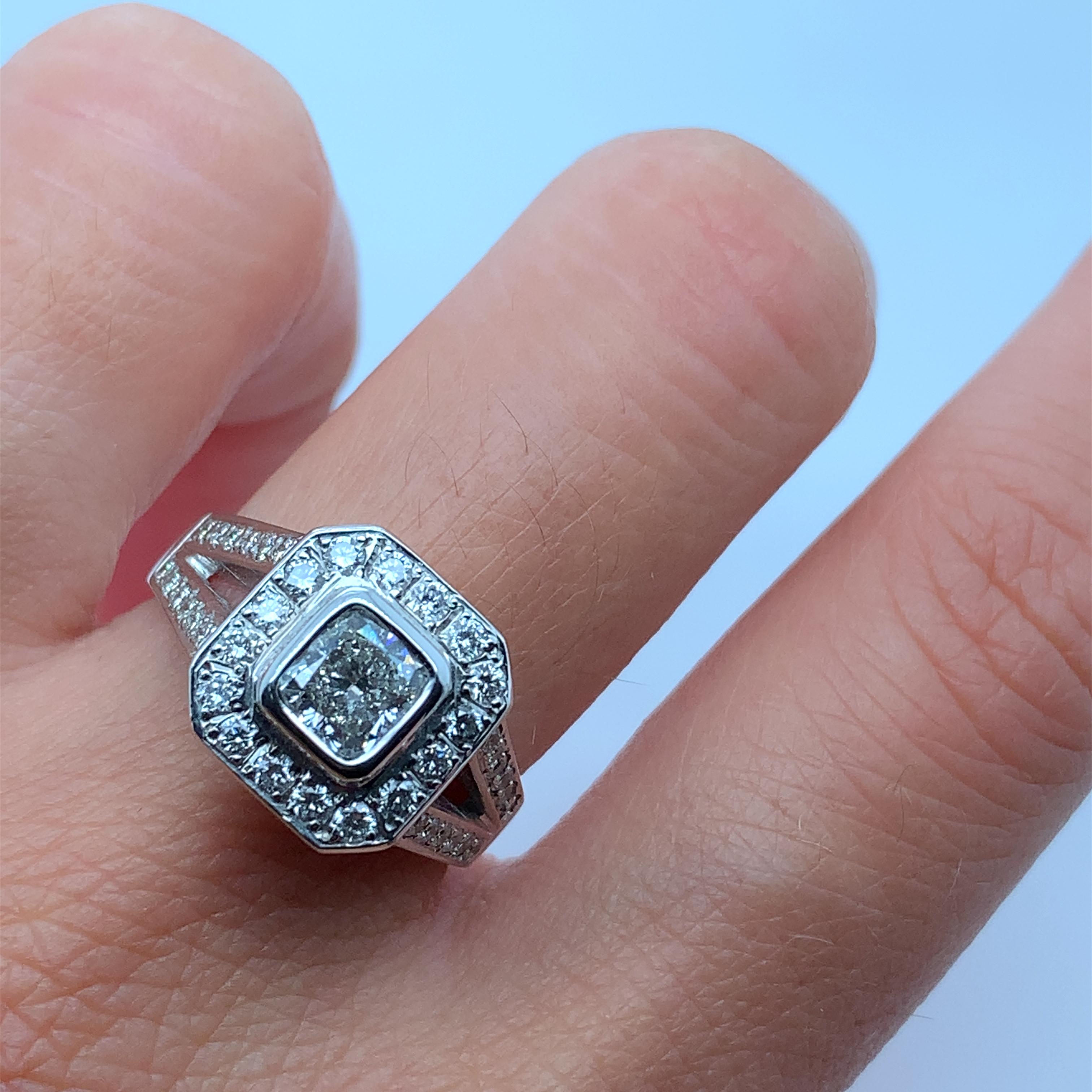 This exquisite engagement band features a stunning 1.50ct cushion diamond set in a halo of smaller diamonds. Crafted from 18ct white gold, this ring is of the highest quality and comes with a valuation for your peace of mind. The cushion diamond has