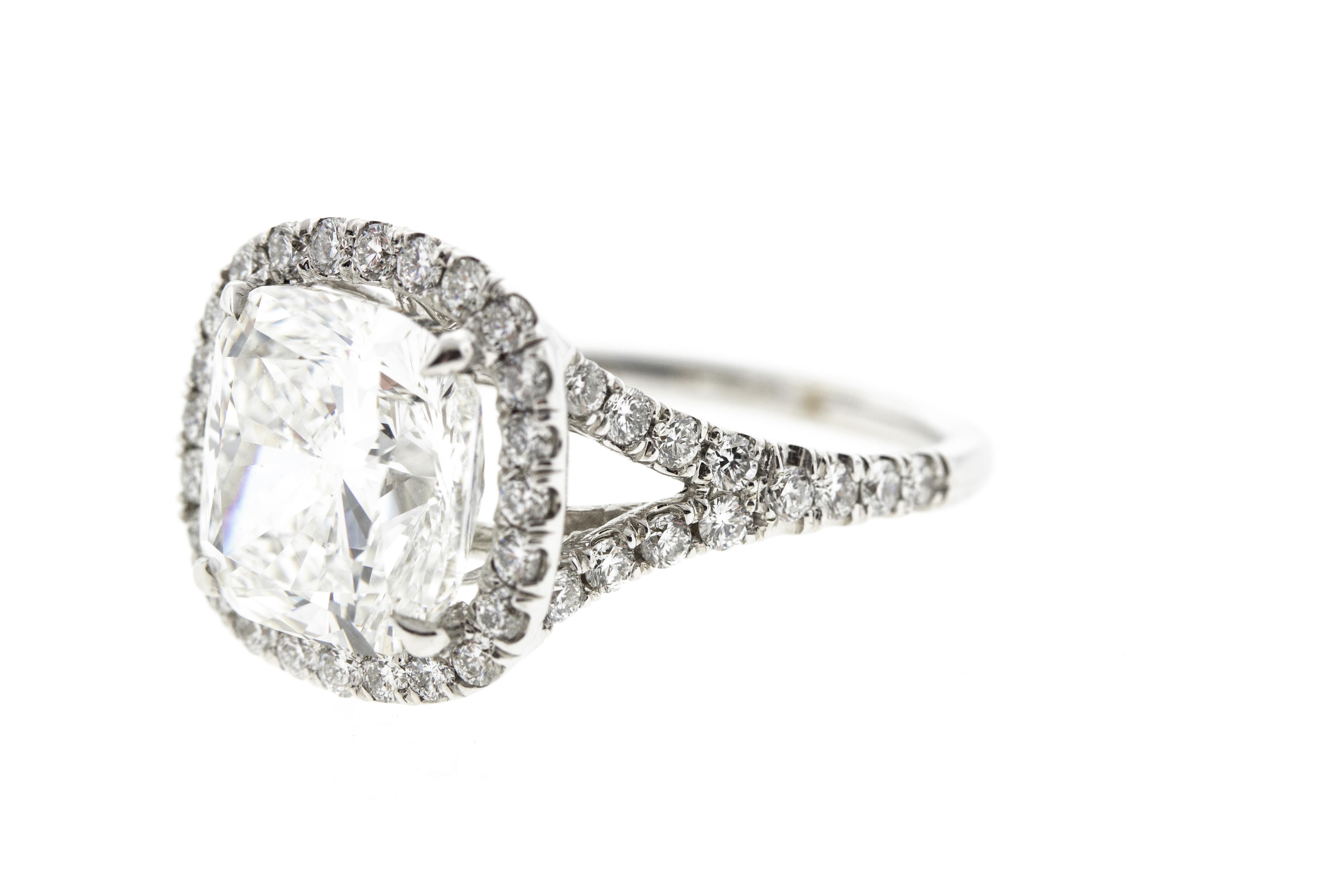 This cushion diamond halo engagement ring features a 1.74 F SI1 GIA certified cushion center diamond and is surrounded by a diamond halo and diamonds on the shank for a total carat weight of 2.31 in a 14K white gold setting. 