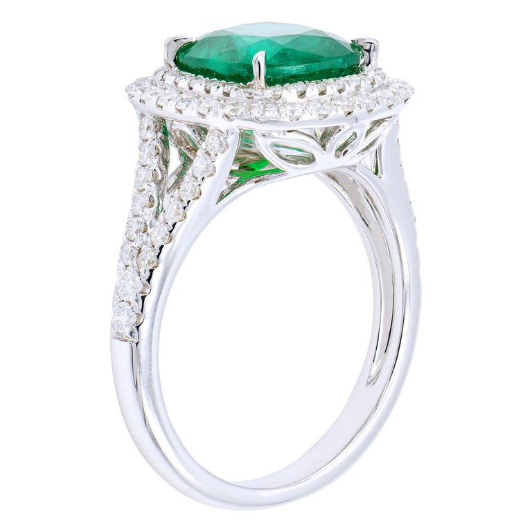This stunning ring has a 2.78 carat cushion cut emerald in the center which is surrounded by 84 round VS2, G color diamonds in a double halo, and going around the band. The diamonds total 0.66 carats with 18 karat white gold. The emerald ring totals