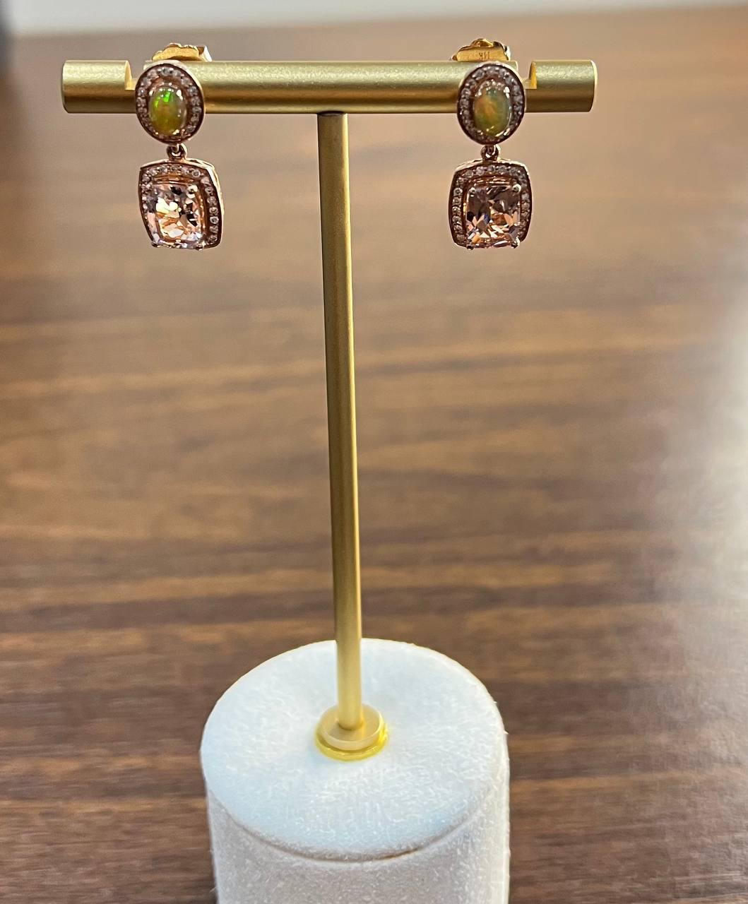 Questi sofisticati orecchini sono realizzati con precisione: ogni orecchino presenta un opale cabochon nella parte superiore, circondato da un'aureola di diamanti bianchi che creano un contrasto sorprendente. In basso è sospesa una morganite rosa