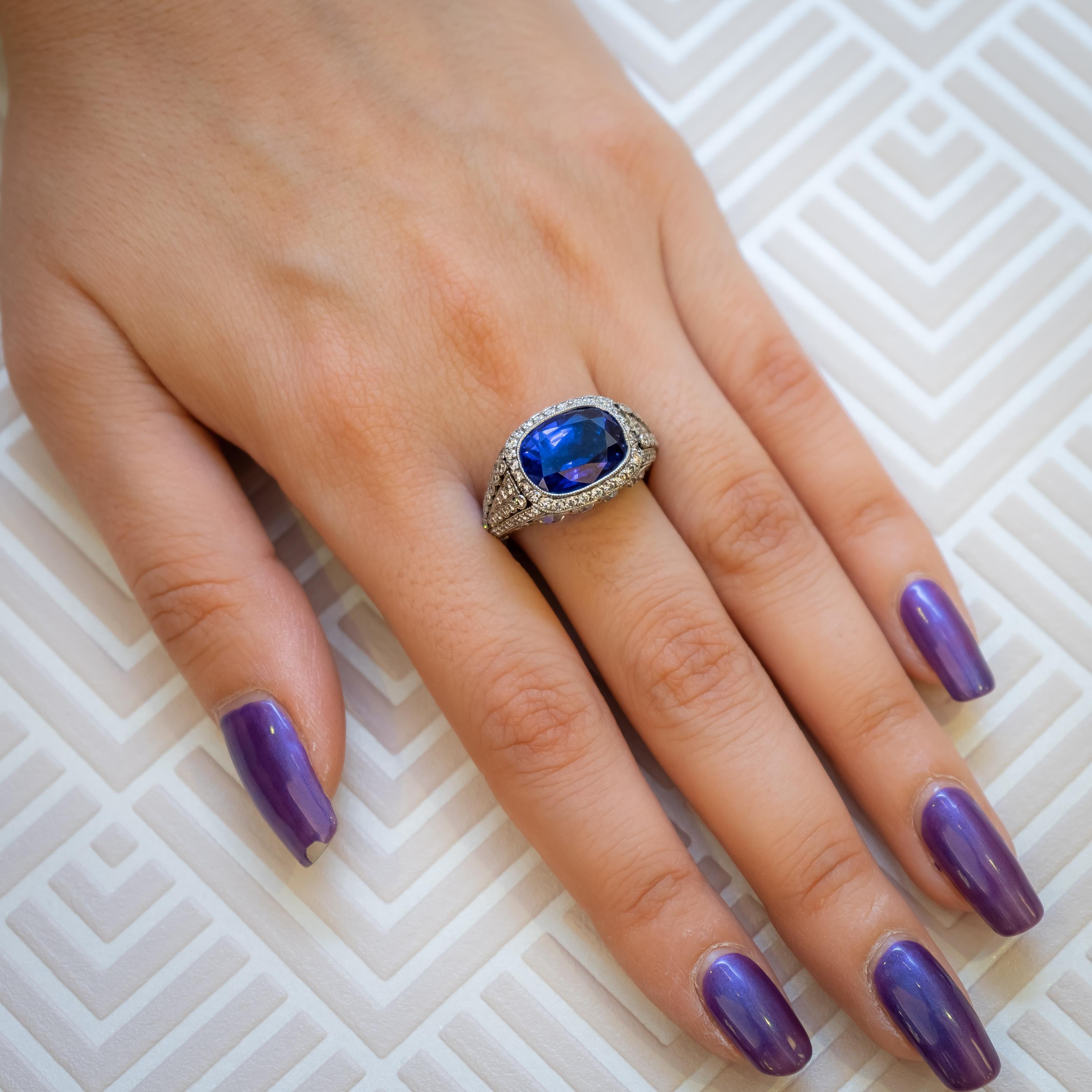 A sapphire and diamond ring set with an 8.64ct cushion-cut sapphire in the centre, with diamonds set in the surround, shoulders and bezel and with calibré-cut sapphires set around the finger bezel, mounted in platinum. With an accompanying GCS