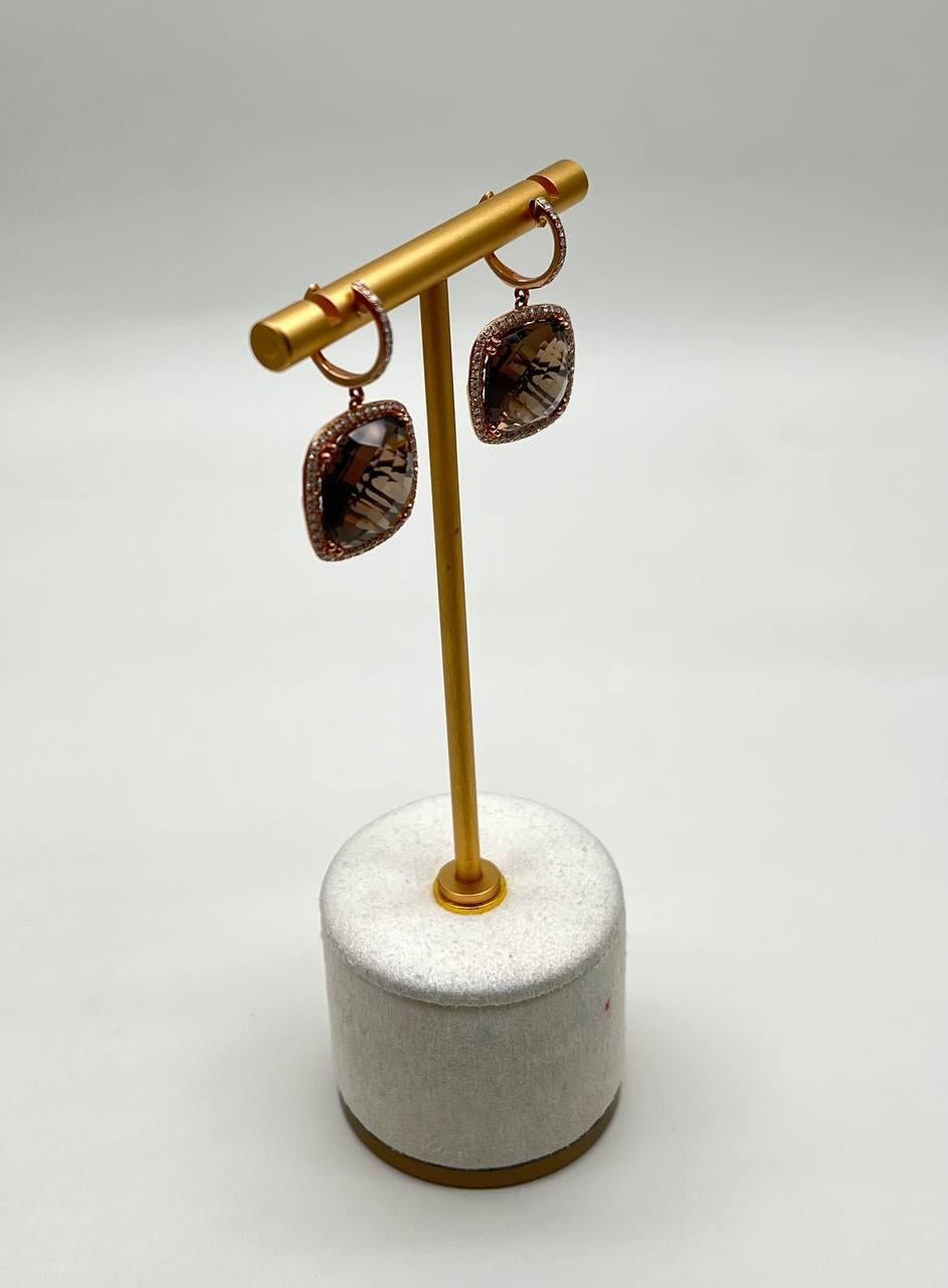 Eleganza e precisione: questi orecchini presentano un sorprendente design quadrato con un quarzo marrone sfaccettato al centro, circondato da una delicata aureola di splendidi diamanti. Oro bianco 14K. 0,67 CTW Diamanti. 20,33 CTW Quarzo Fumè.