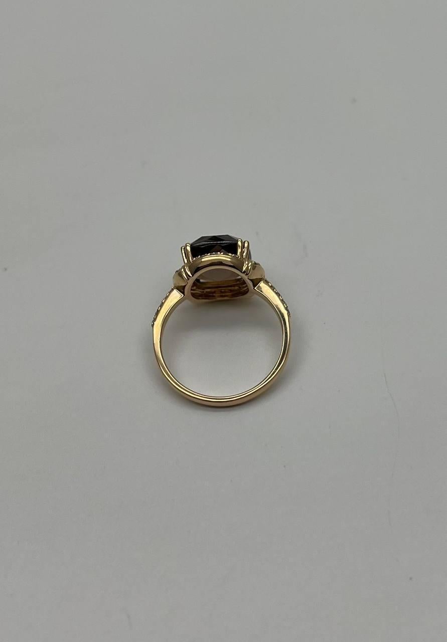 This exquisite ring is crafted with precision. The centerpiece features a stunning faceted smoky quartz, surrounded by a halo of sparkling diamonds. The band is adorned with additional diamonds, enhancing its luxurious appeal. The piece is in