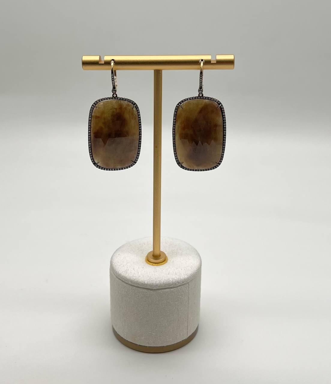 Exquisite dangle earrings featuring rich brown sapphires, totaling 59.35 carats. Each stone is framed by a delicate halo of sparkling white diamonds, weighing 0.65 carats in total. Crafted in luxurious 14k yellow gold. Contemporary elegance.