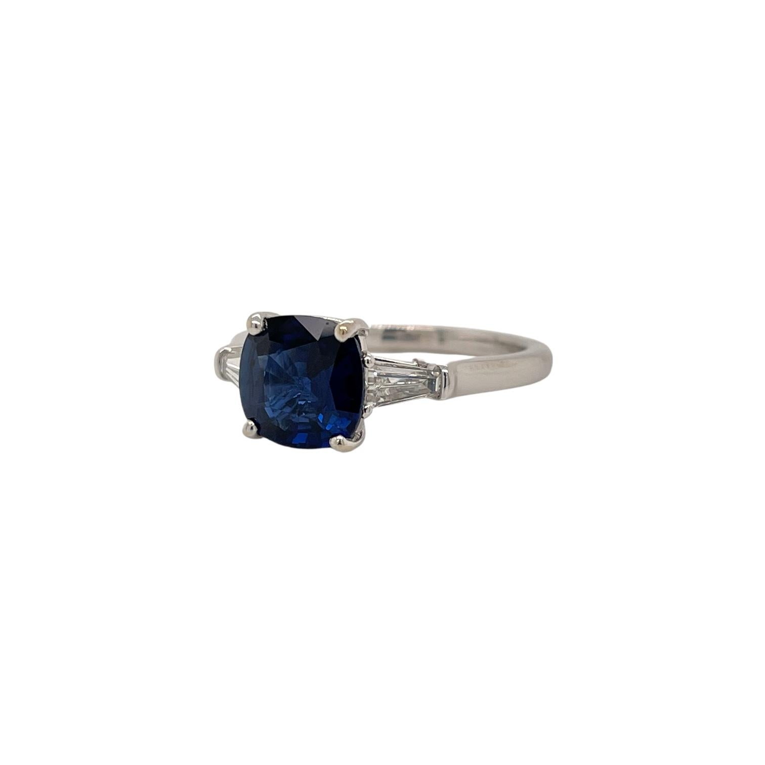 This beautiful royal blue cushion sapphire and baguette diamond ring is set in 18K white gold and includes a certification from Bellerophon. This ring is sure to please you with the beautiful sparkle of the sapphire and baguette diamonds. The center