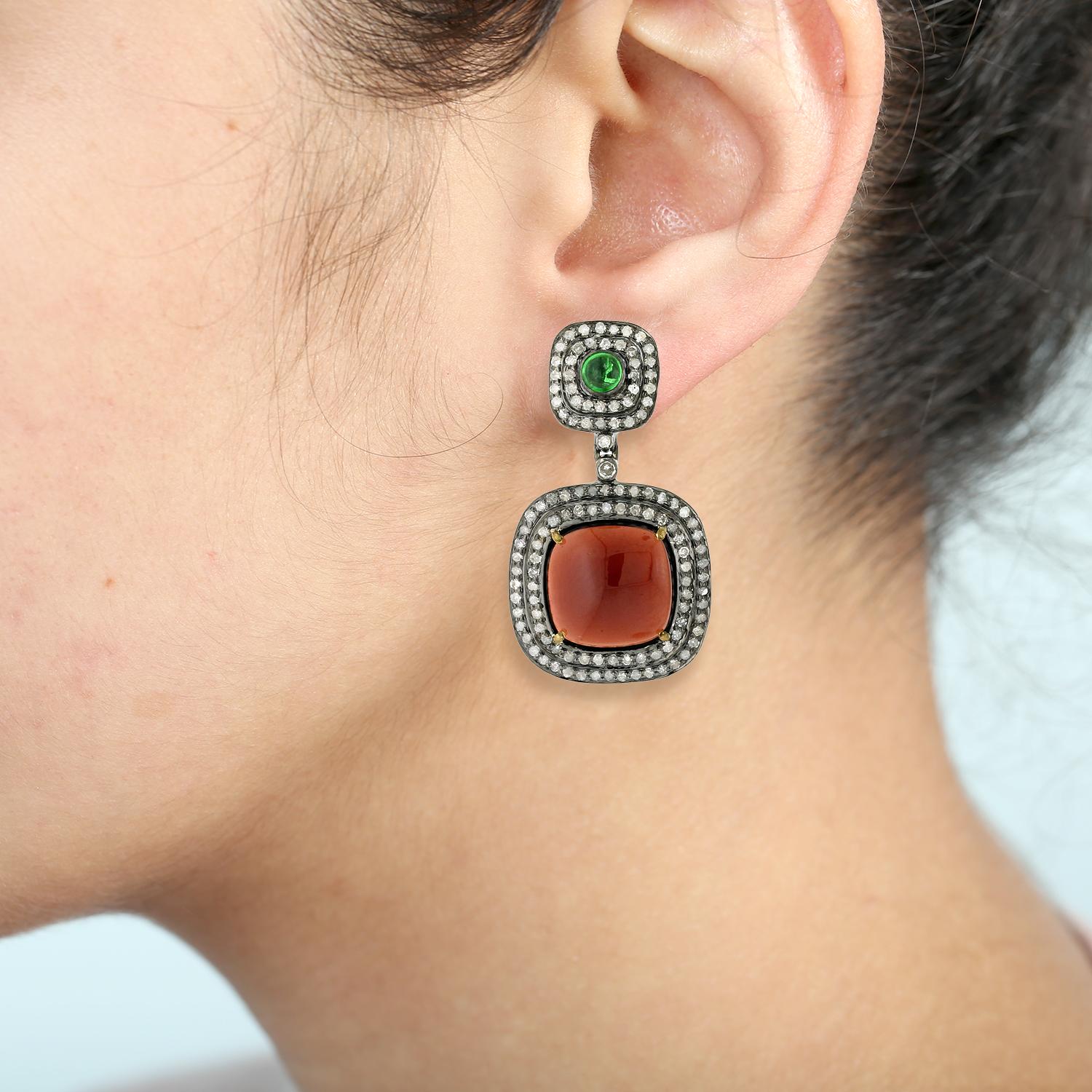 Add a pop of color to your jewelry collection with these beautiful Cushion Shaped Garnet & Tsavorite Earrings. Expertly crafted in 18k gold and silver, these earrings feature cushion shaped garnet and tsavorite gemstones, set in elegant and timeless