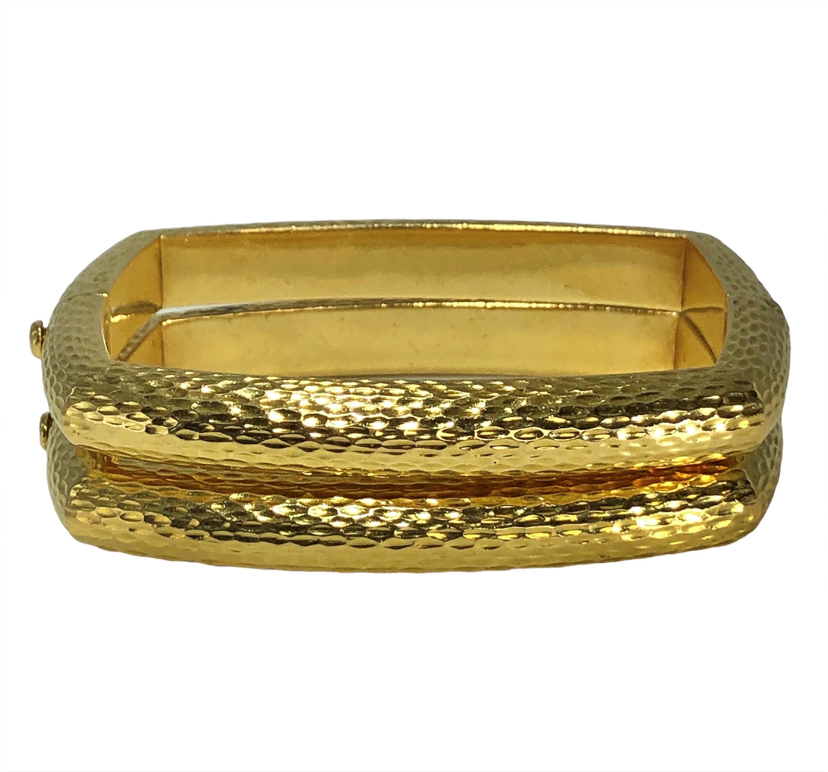 This stylish, matching pair of cushion shaped, bark finish, David Webb 18K yellow gold bangle bracelets make an edgy statement for the wearer. Both bracelets are hinged on one side with bark finished flip safety catches. Made to fit a small wrist.