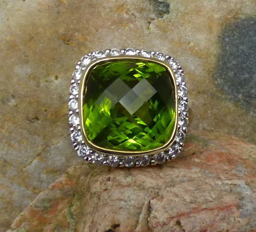 Exquisite rose cut cushion shaped Peridot (9.22ct) is surrounded by 24 Diamonds (.94ct.). Total size of the front  of the ring is 18X17mm. This handmade 18k yellow gold ring is hallmarked by the Dublin Assay Office.
The ring is currently an American