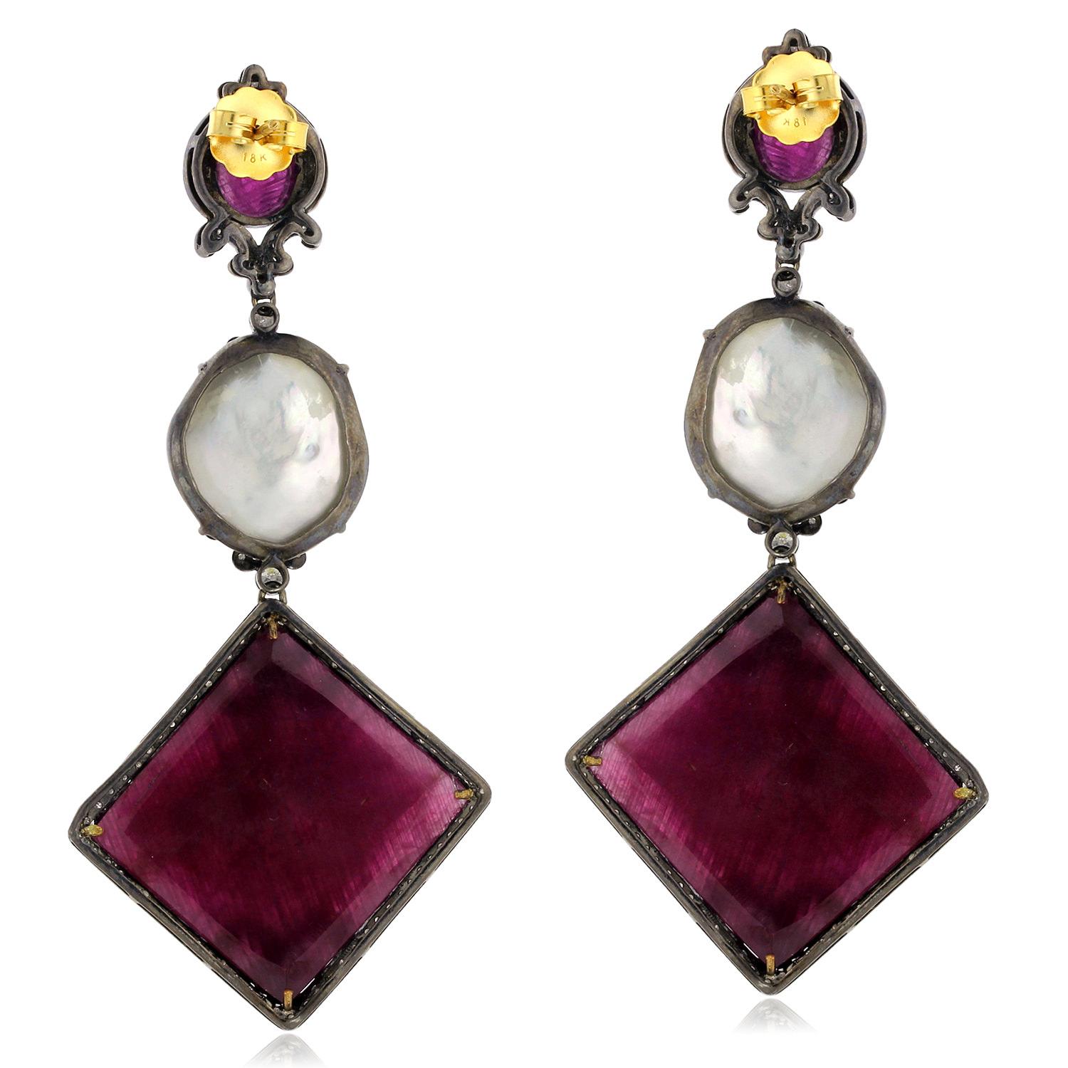 These breathtaking cushion-shaped ruby earrings are a true showstopper. The rich red rubies are the centerpiece of these earrings, and are connected to a lustrous pearl by a row of sparkling diamonds. The diamonds are encased in a delicate pave