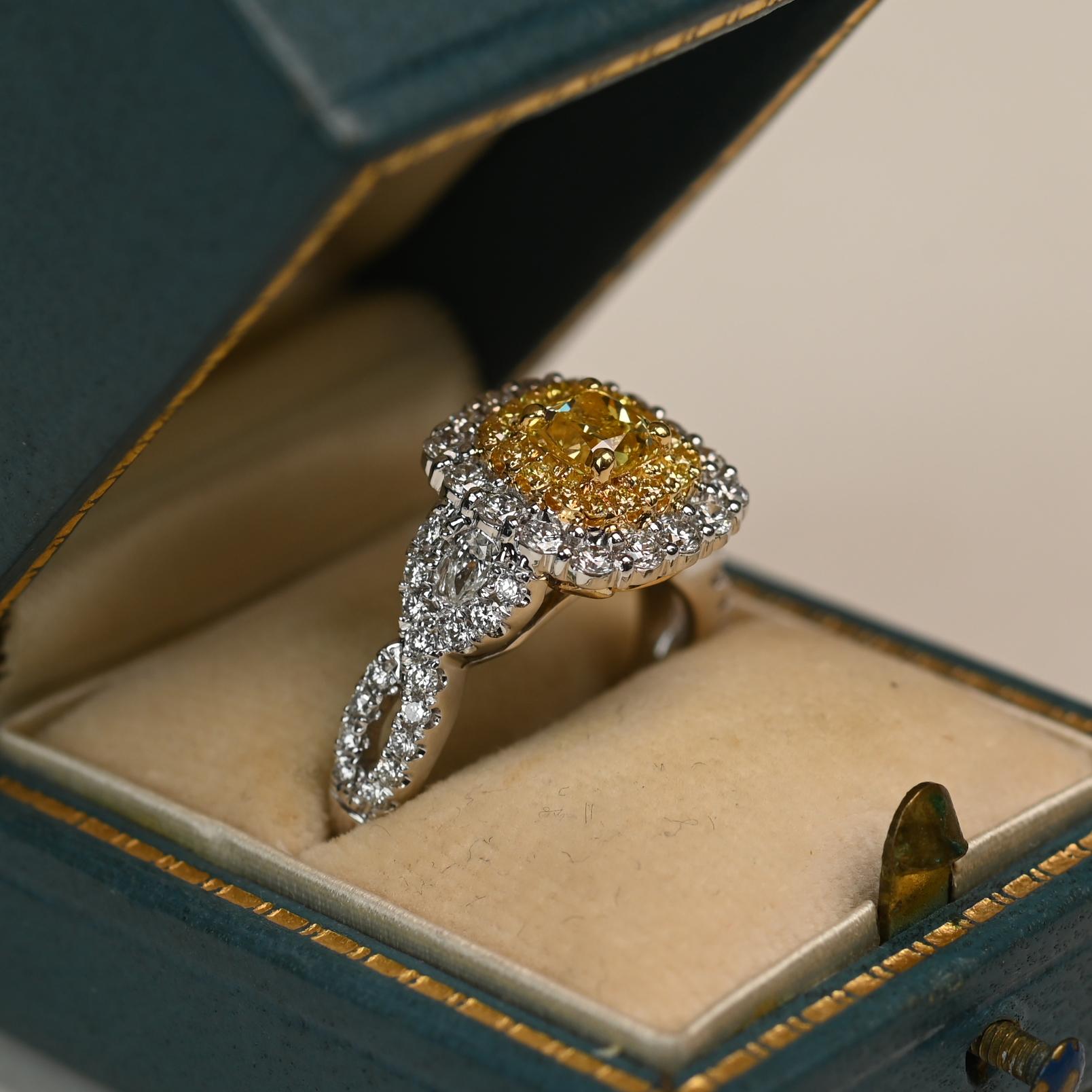 Questo anello presenta al centro un diamante giallo con taglio a cuscino del peso di circa 0,60 carati e una purezza VS1. Il diamante è evidenziato da una doppia aureola di diamanti bianchi e gialli, incastonati in un design a punte condivise che ne
