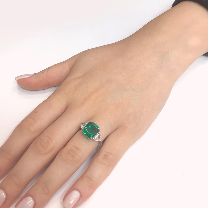 This elegant gemstone ring is crowned with a beautiful cushion cut Zambian emerald 5.45 carat and paired with two half moon diamonds 1.06 carat at the side in G-H Color Clarity VS.  Additionally, small gold accents are at the joints on a platinum