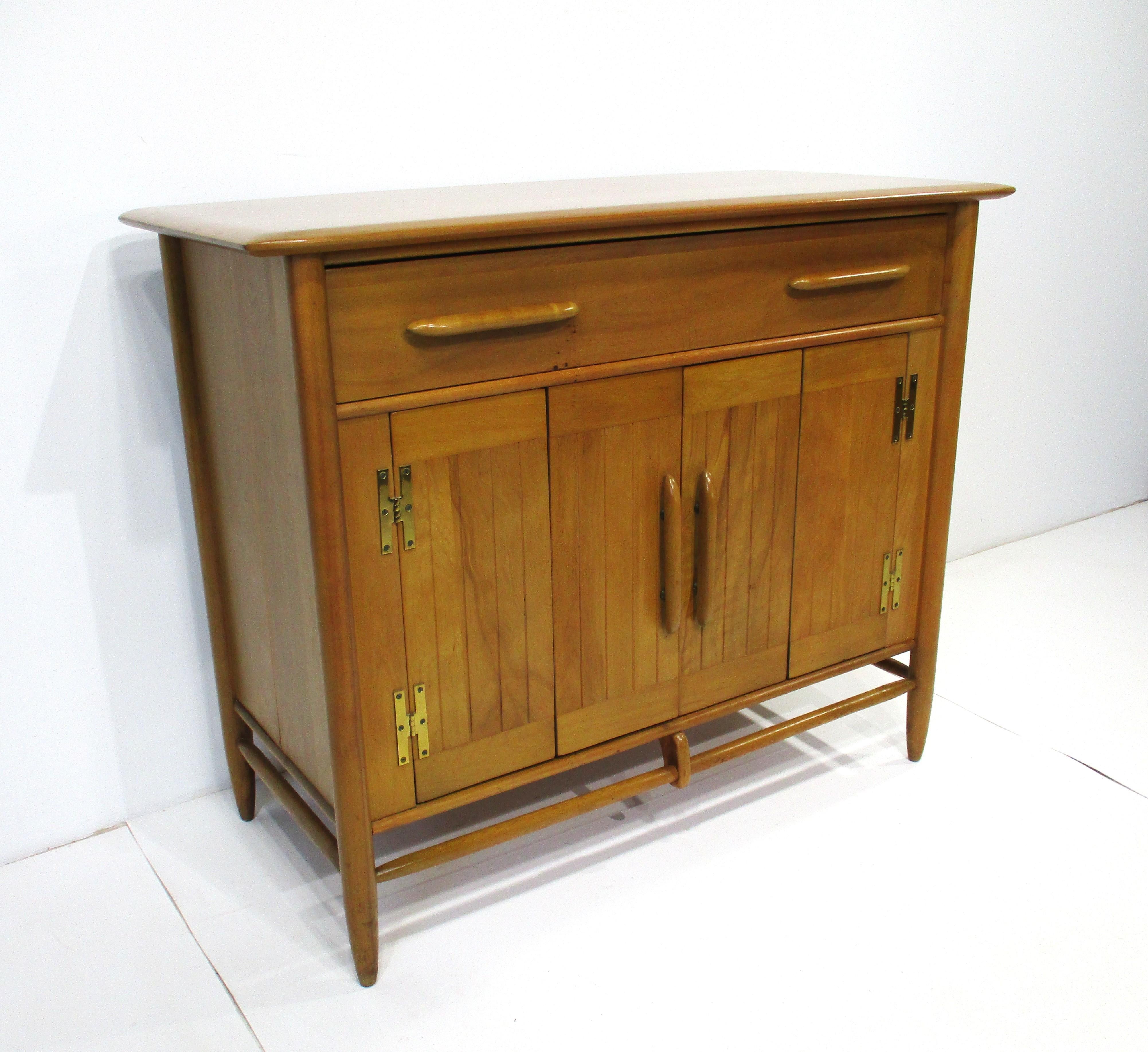 A very well crafted sever cabinet with bi-fold doors a fixed shelve and one upper drawer having dividers. Constructed from hard old growth northern birchwood known for its beautiful graining with solid brass hardware and long pulls mixing the unique