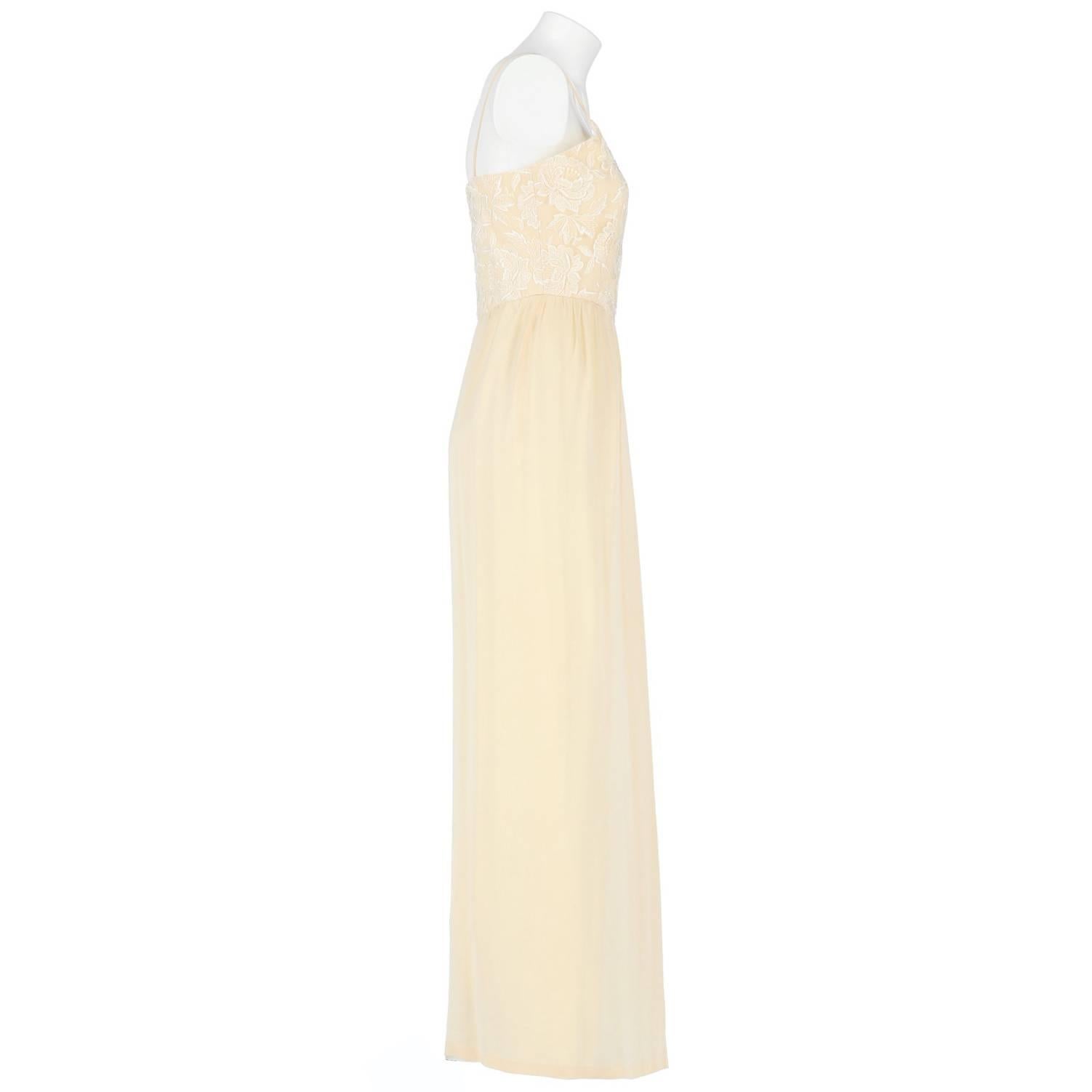 Splendid custard silk wedding dress. It features thin shoulder straps, a white lace bodice with floral decoration, wide skirt and lateral zip closure. The item is vintage, it was produced in the 60s and is in very good conditions, it only has the