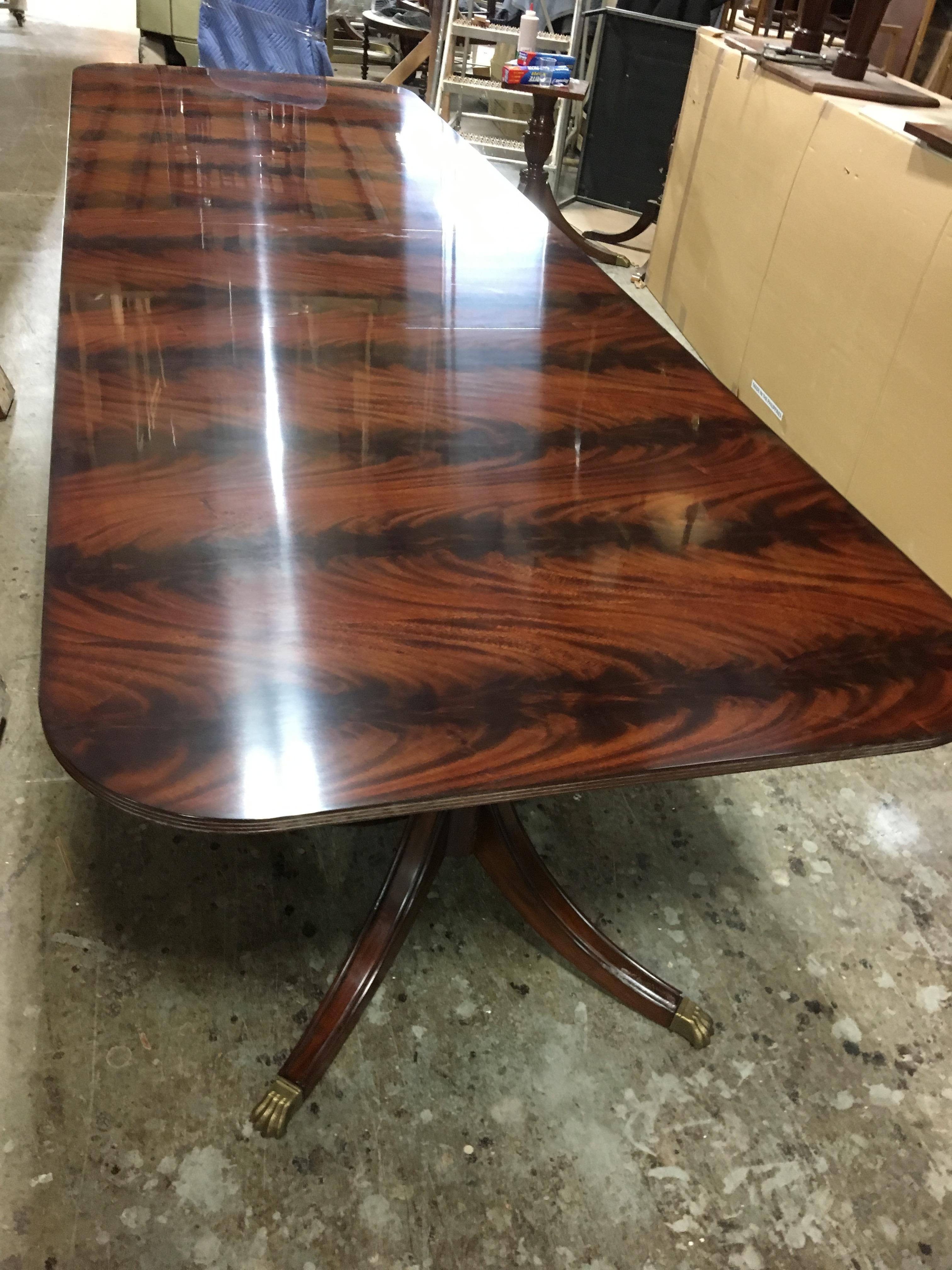 This is a made-to-order traditional mahogany dining table made in the Leighton Hall shop. It features a field of reverse slip-matched swirly crotch mahogany from West Africa. It has a hand rubbed and polished semigloss finish. The Sheraton-style