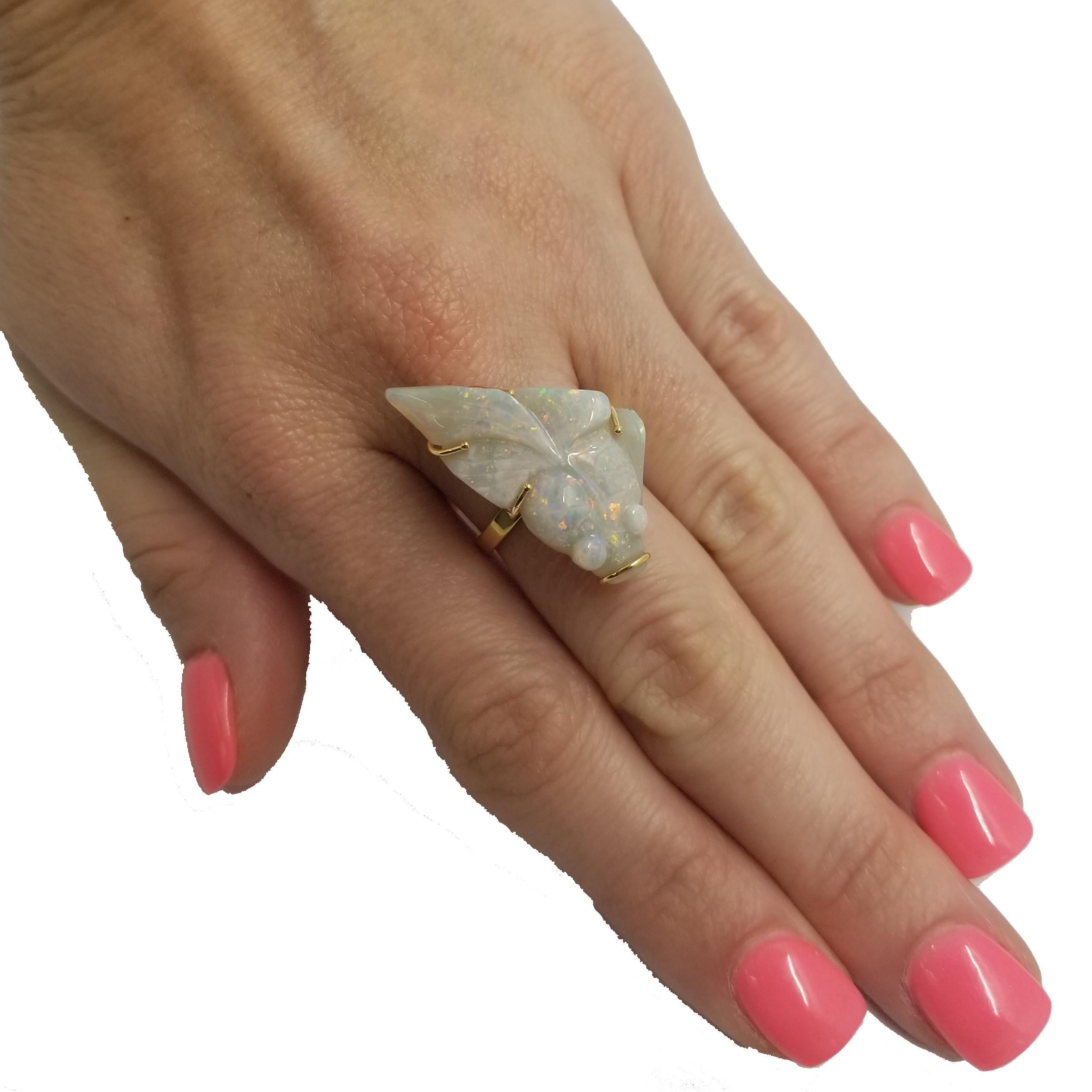 Handmade one-of-a-kind 14 karat yellow gold ring featuring an opal fish carving. The opal weighs 12.77 carats and has gorgeous play-of-color including red, pink, green, and blue. The carving is held by 4 prongs and a loop with open gallery