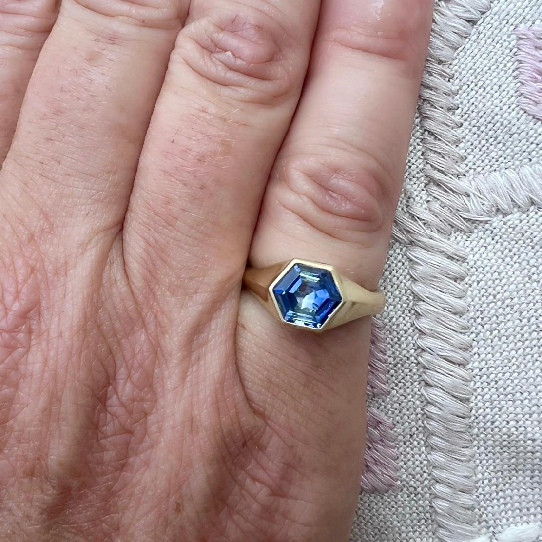 A truly unique beauty! This custom 18 karat yellow gold ring features a stunning unheated hexagon cut blue sapphire expertly bezel set. The unheated sapphire weighs 2.09 carats, exhibits wonderful light return and rich evenness of color saturation,