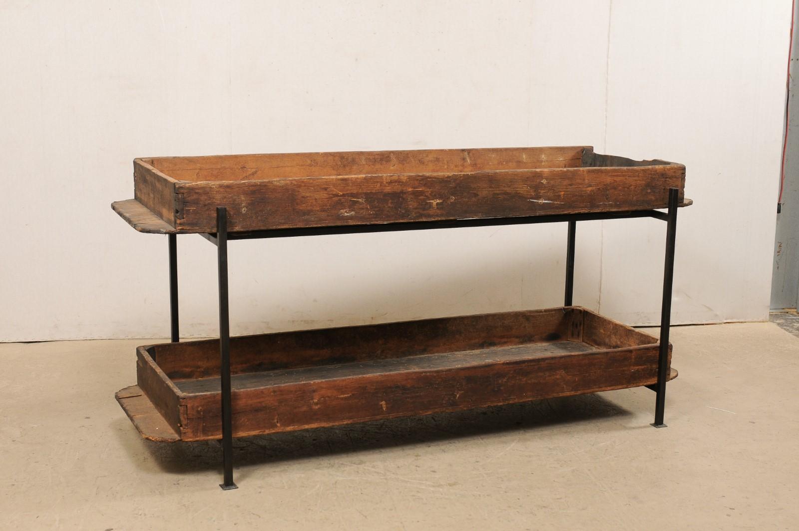 A custom created two-tiered table from antique French baker's bread risings shelves. This long table, just under 7 feet in length, features a rectangular-shape, fashioned from two wooden French bakery shelves, used in the rising of bread loaves,