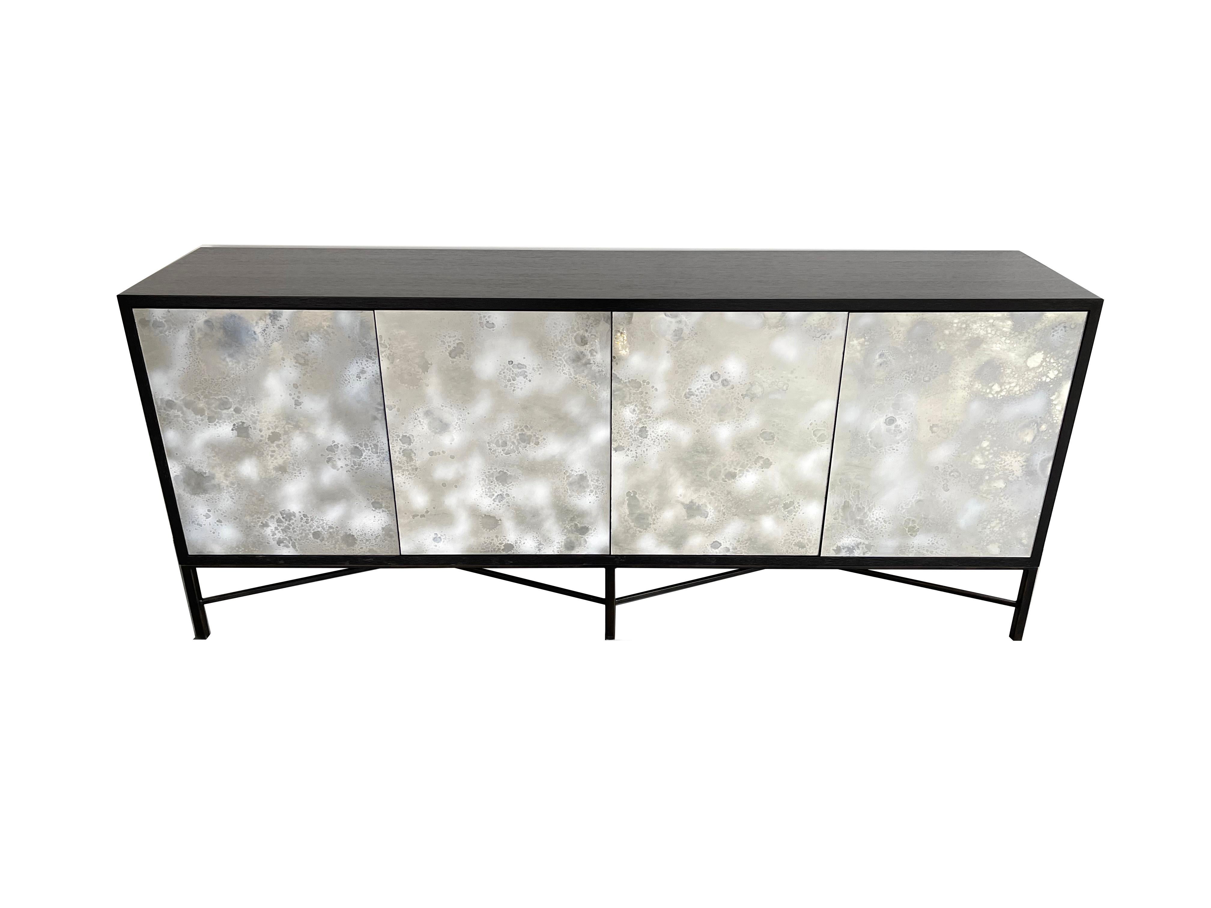 The Industrial buffet or credenza by Ercole home has a 4-door front with touch latch.
The wood is finished in a Wenge on oak.
Hand-painted white dust eglomise glass are on the door surfaces which is handpainted in out Brooklyn NY studio.
The