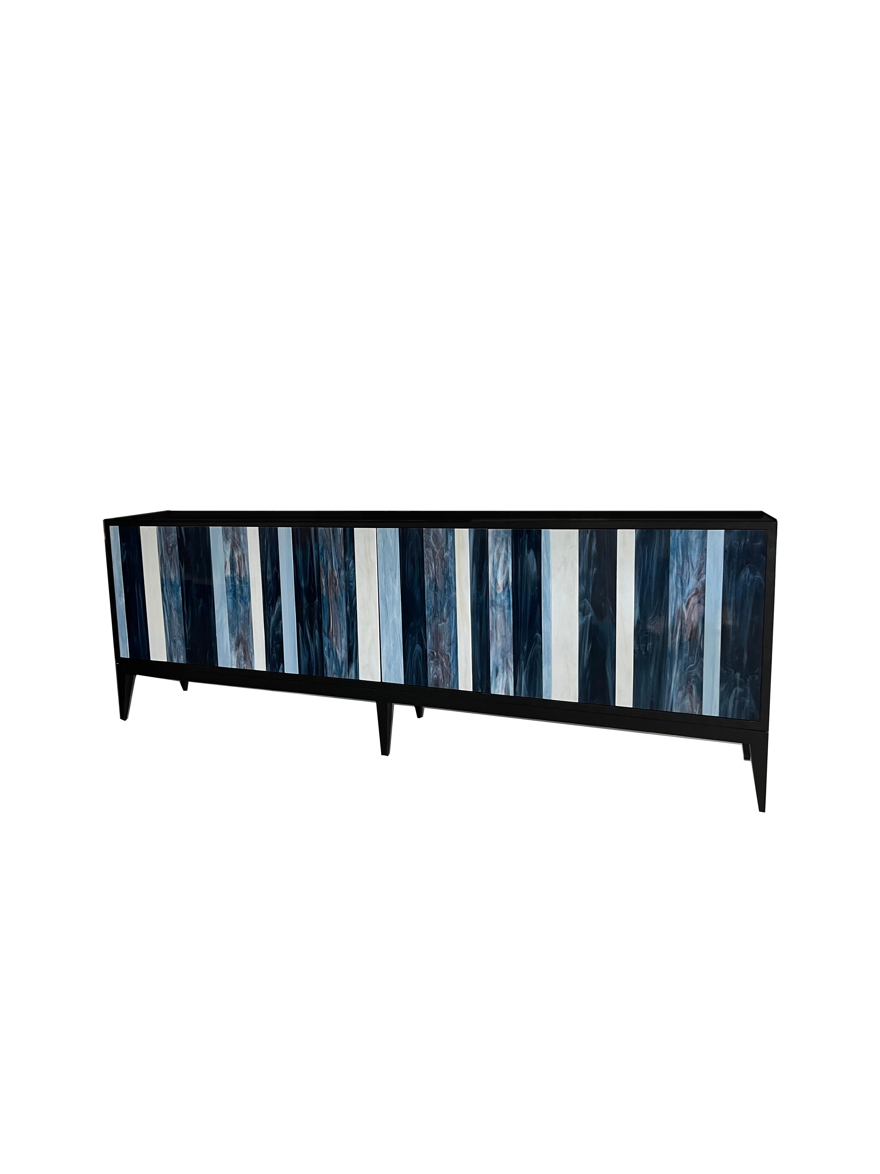 The Linea Milano buffet by Ercole home has a 6-door front, with rich dark Wenge wood finish.
Handcut glass stripes in ivory, French blue, electric blue, and cloudy notte decorate the surface of doors.
There is one adjustable interior shelf with