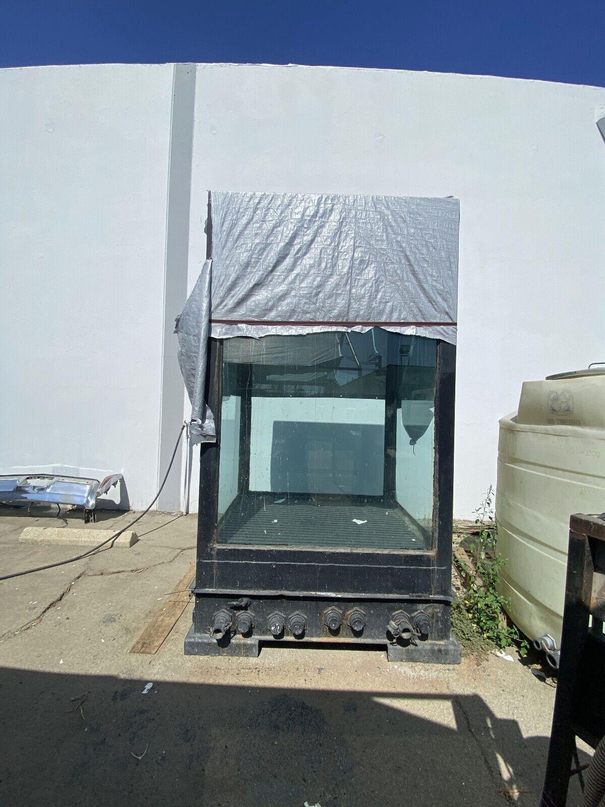 Gran depósito de agua de cristal de 13' de altura y 1631 galones con base de acero, con una base de acero de calidad industrial con el estilo de un acuario industrial de los años 30. El depósito está hecho de paredes acrílicas de 5 cm de grosor
