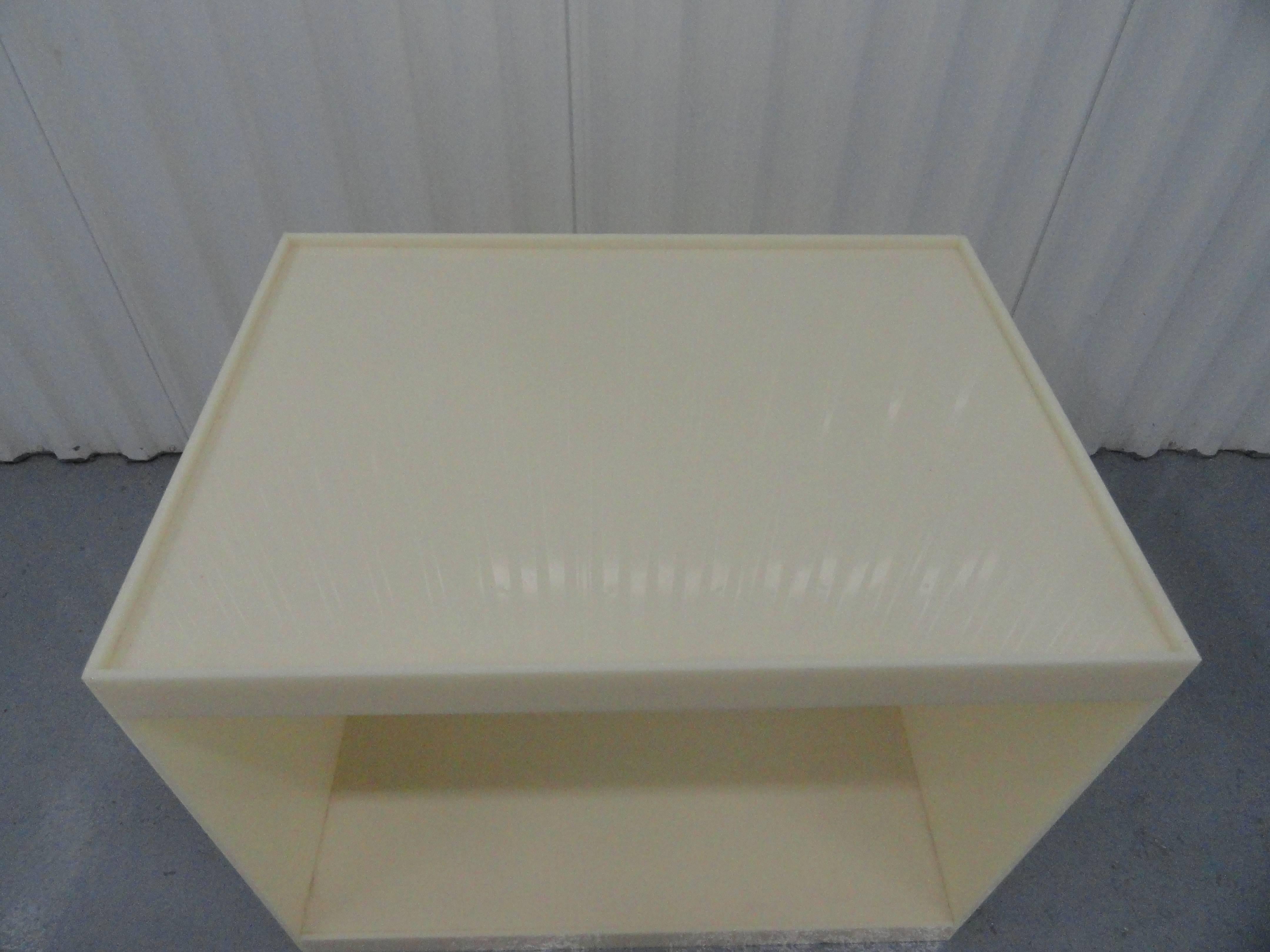 Custom acrylic side table in a cream color.