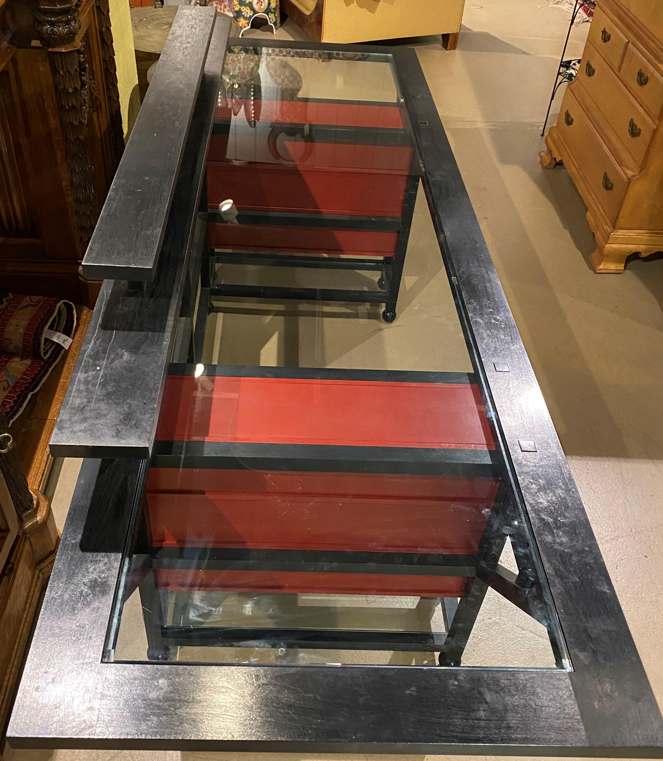 A beautiful form custom Aesthetic design desk or server in cherry wood and glass top, with ebonized frame, supported by two red painted pedestal bases, each with three drawers and brass teardrop pulls. The desk was made by Dublin, NH furniture maker