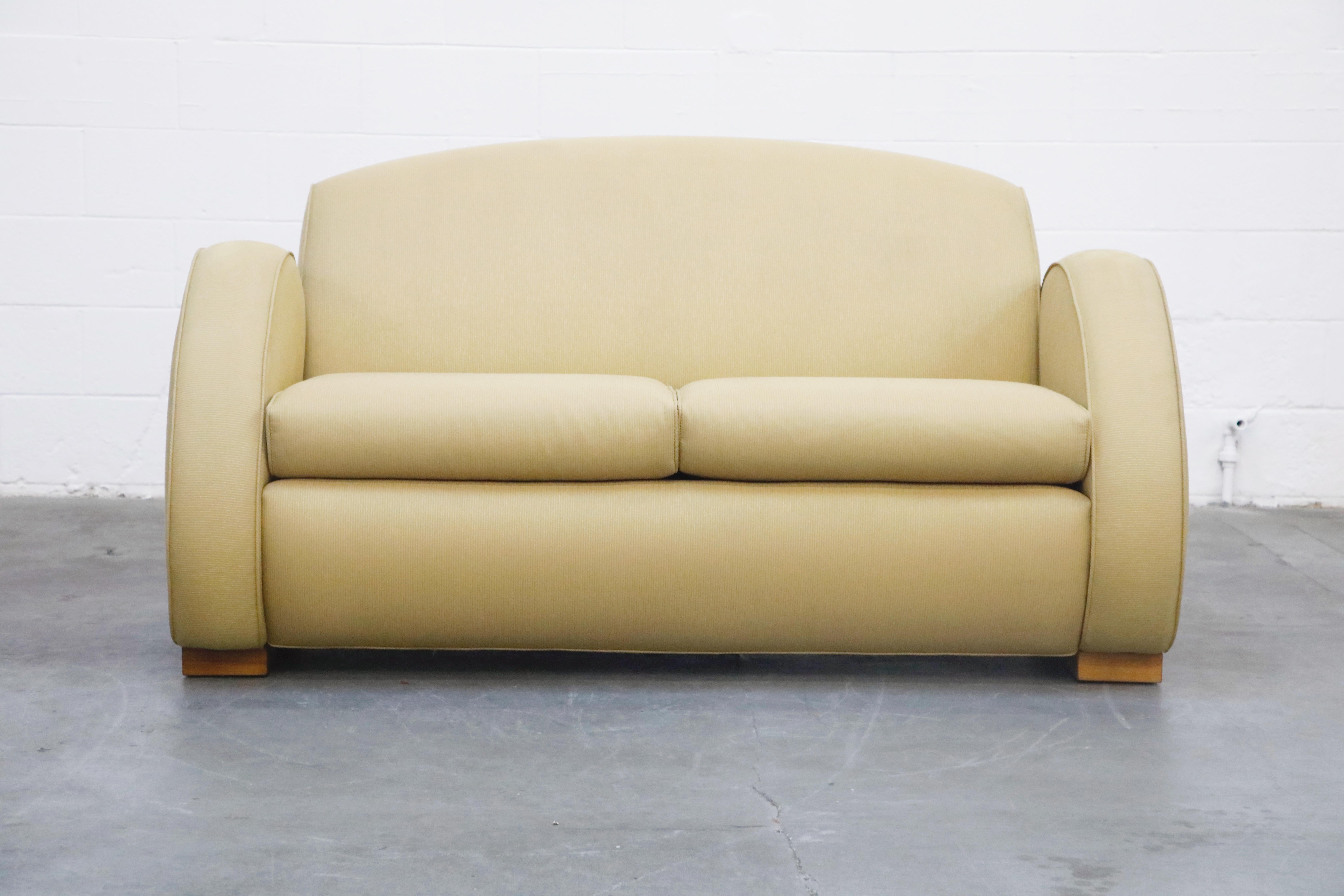 Custom-made and high-quality Art Deco style loveseat upholstered in a yellow fabric. This deep-seated settee comprise of comfortably reclined back and oversized rounded arms which reflect the Art Deco style. These chairs sit atop sturdy art deco