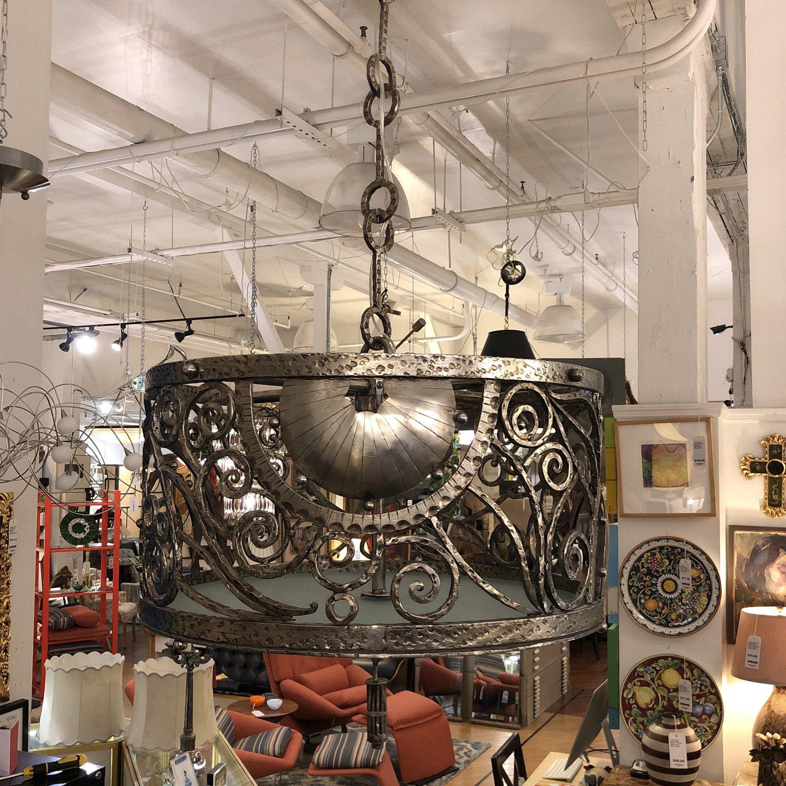A custom metal drum chandelier. A sight of fine craftsmanship by skilled artisans. The drum is based on a multi designs of welded swirls and curves. The metal shows natural hammered technics. The bottom of the pendant has a frosted glass to