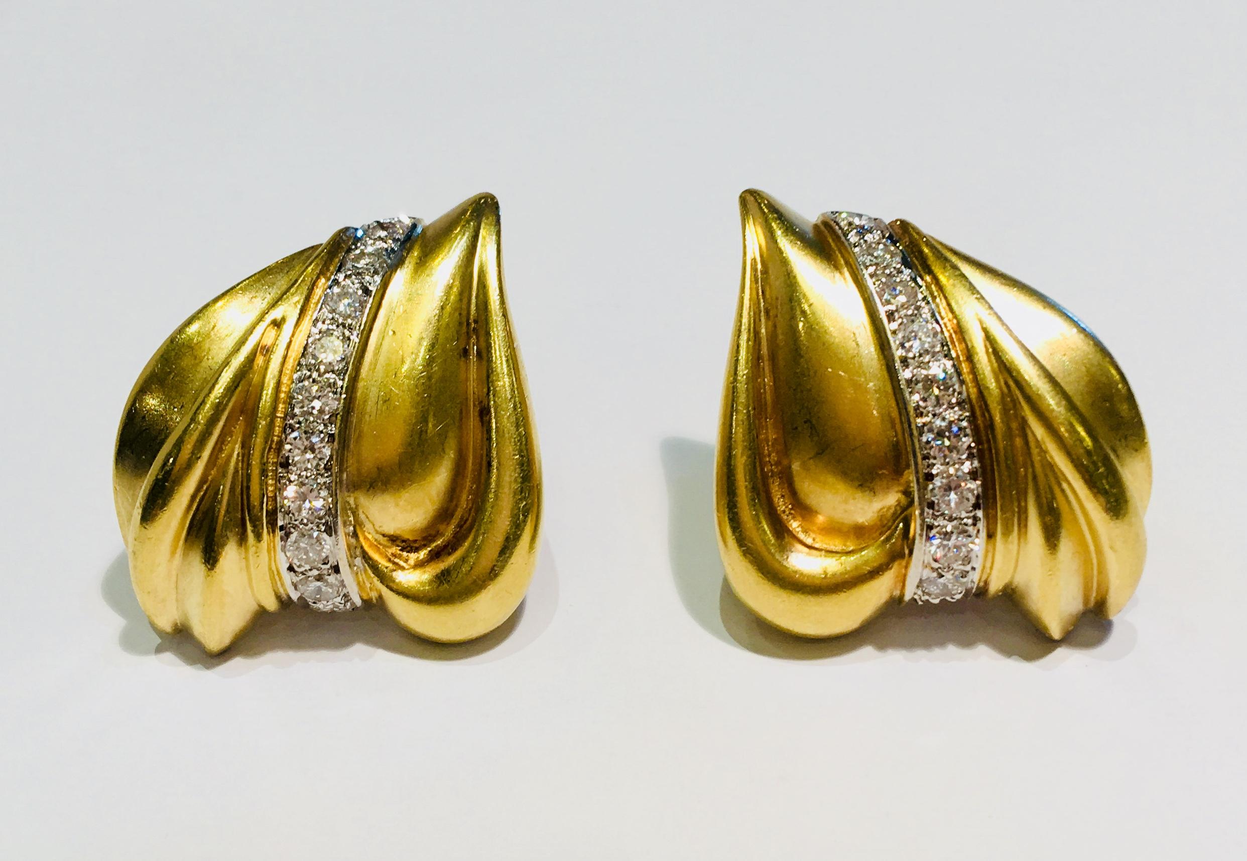 Die eleganten Ohrringe aus 18-karätigem Gelbgold sind satiniert und haben eine abstrakte, dreidimensionale Herzform mit einer geschwungenen vertikalen Linie aus 10 runden, pflastergefassten Brillanten. 

20 runde Brillanten mit einem Durchmesser von