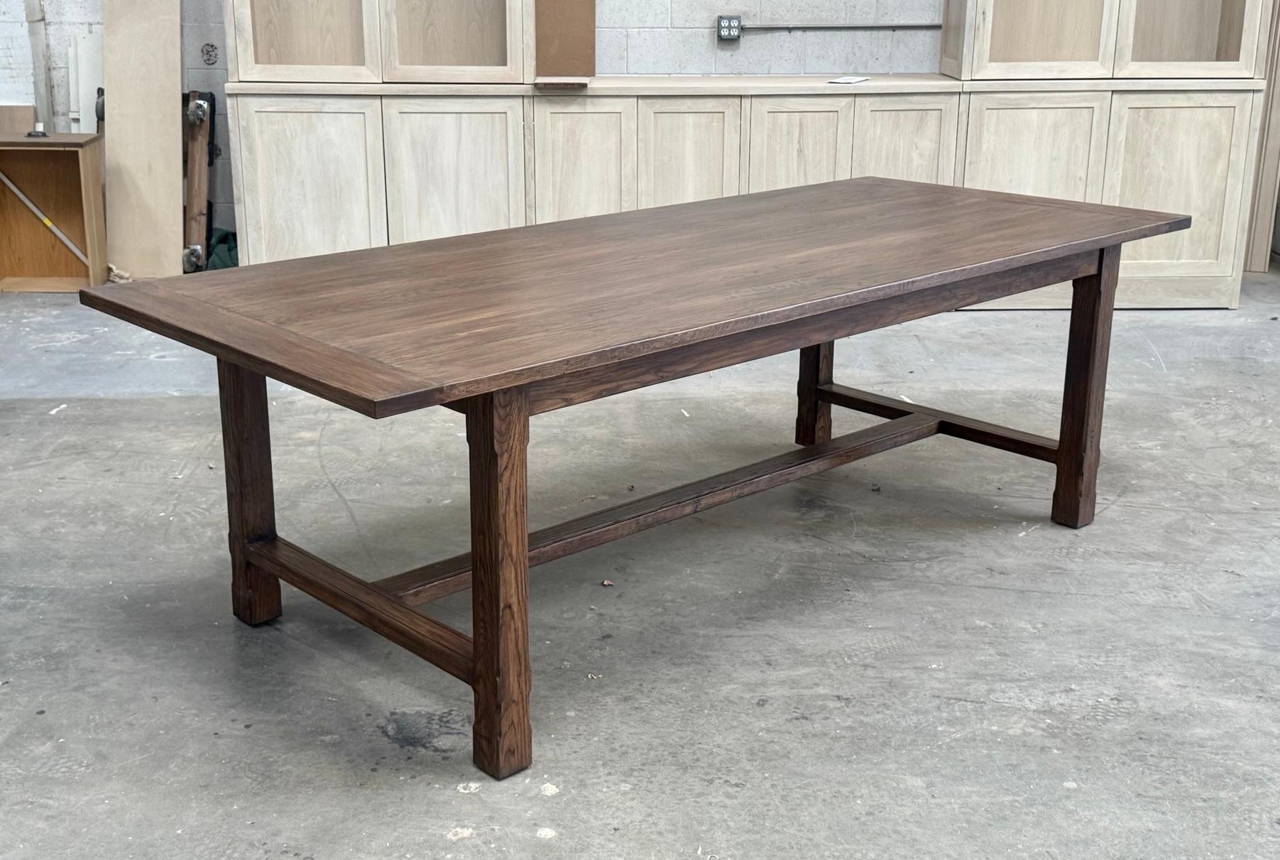 Esta mesa a medida de roble rústico tiene las patas achaflanadas y los travesaños estriados. Aquí se ve en 102