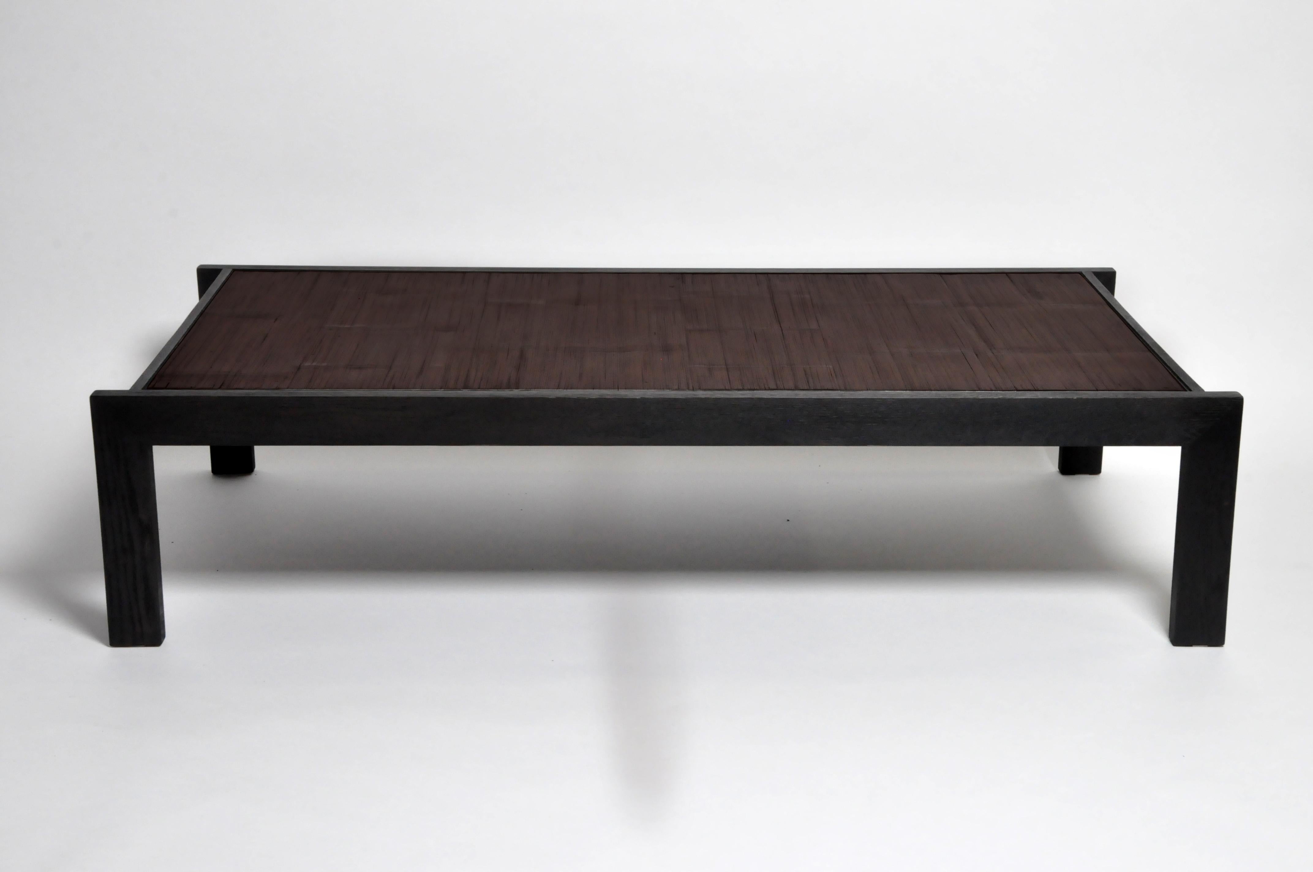 This large custom coffee table is made from a vintage Chinese opium mat. The mat has been affixed to a wooden panel and mounted inside a frame of solid white oak. The opium mat itself is made from slices of bamboo held together with jute rope. The