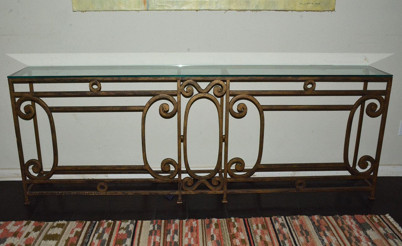 The long baroque style metal console or sofa table has a brushed gilt finish and is handcrafted with elegant scroll-work and detailing. The feet have flat iron pads. The console is newly made from antique fencing. We have additional stock and can