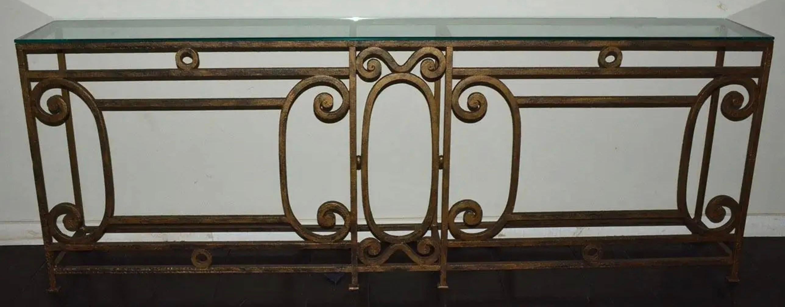 La longue console ou table de canapé en métal de style baroque a une finition dorée brossée et est fabriquée à la main avec des volutes et des détails élégants. Les pieds ont des coussinets plats en fer. La console a été fabriquée à partir de