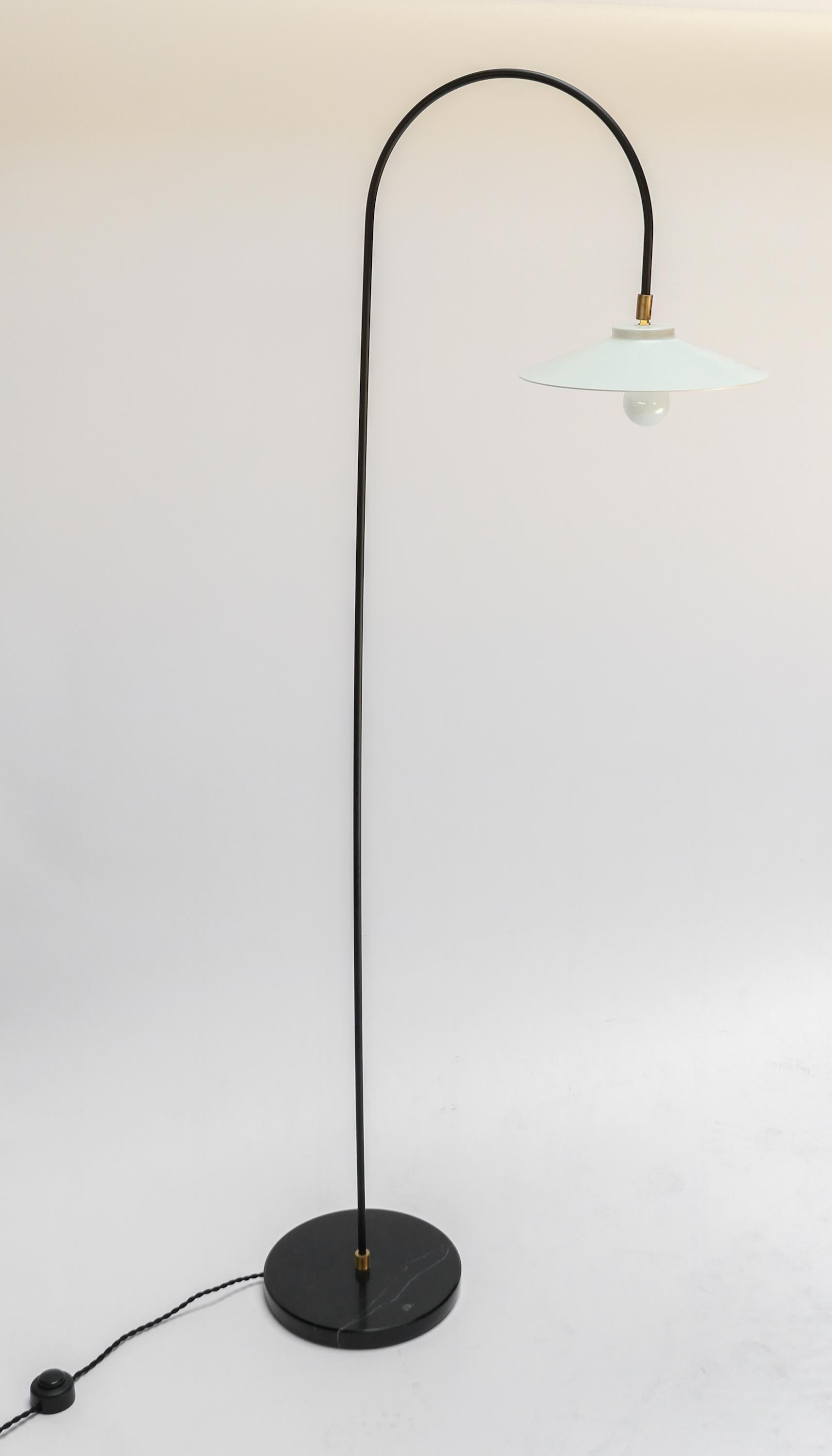 Custom mid century style floor lamp in white and black metal with arching shade and black marble base with brass details by Adesso Imports.

Base is 10