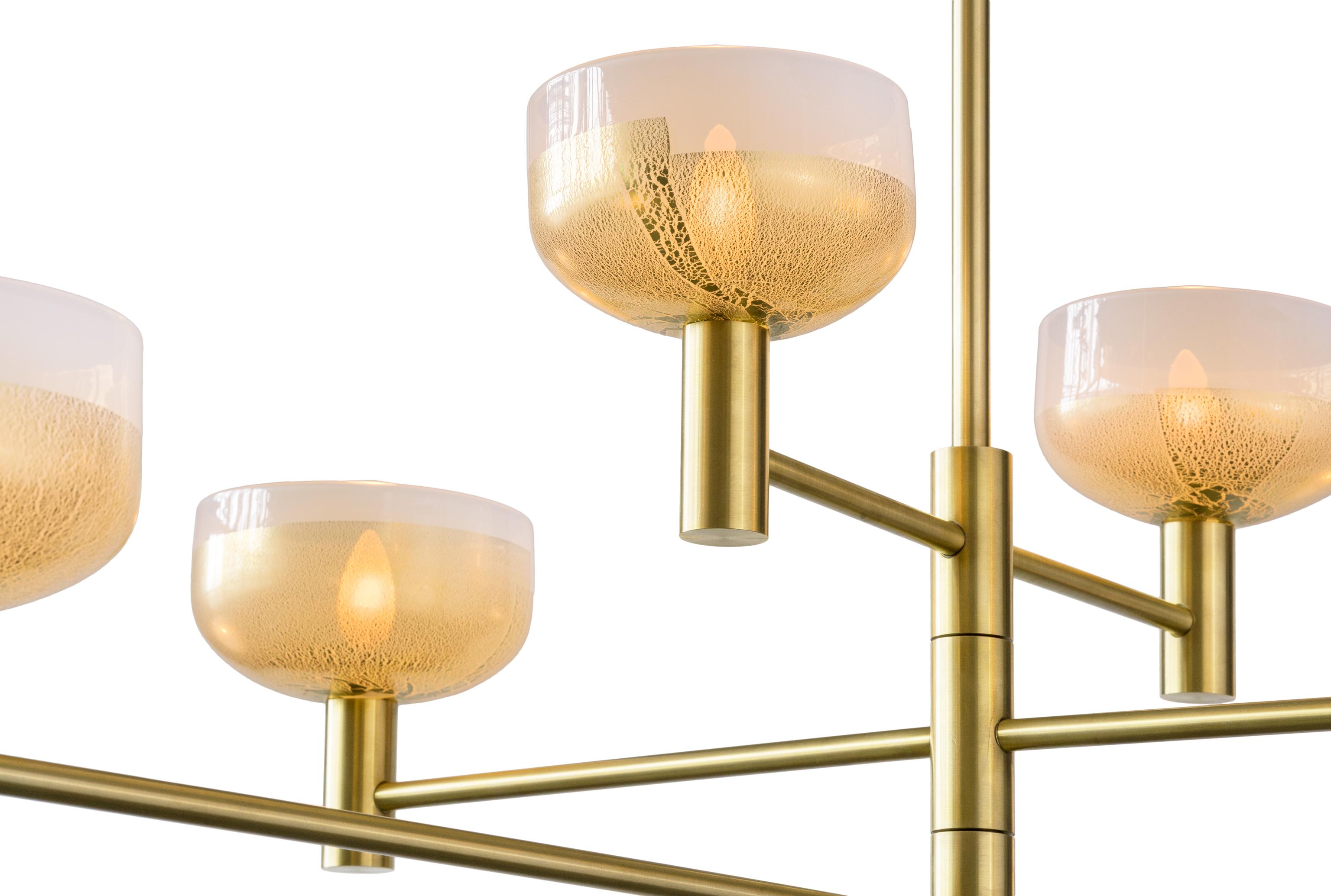 The Otto Luce chandelier was inspired by lighting fixtures found in Italy in the Mid-Century. This original and patented design is made to order with gilded blown glass and hand finished metal, creating a statement chandelier that carries on the