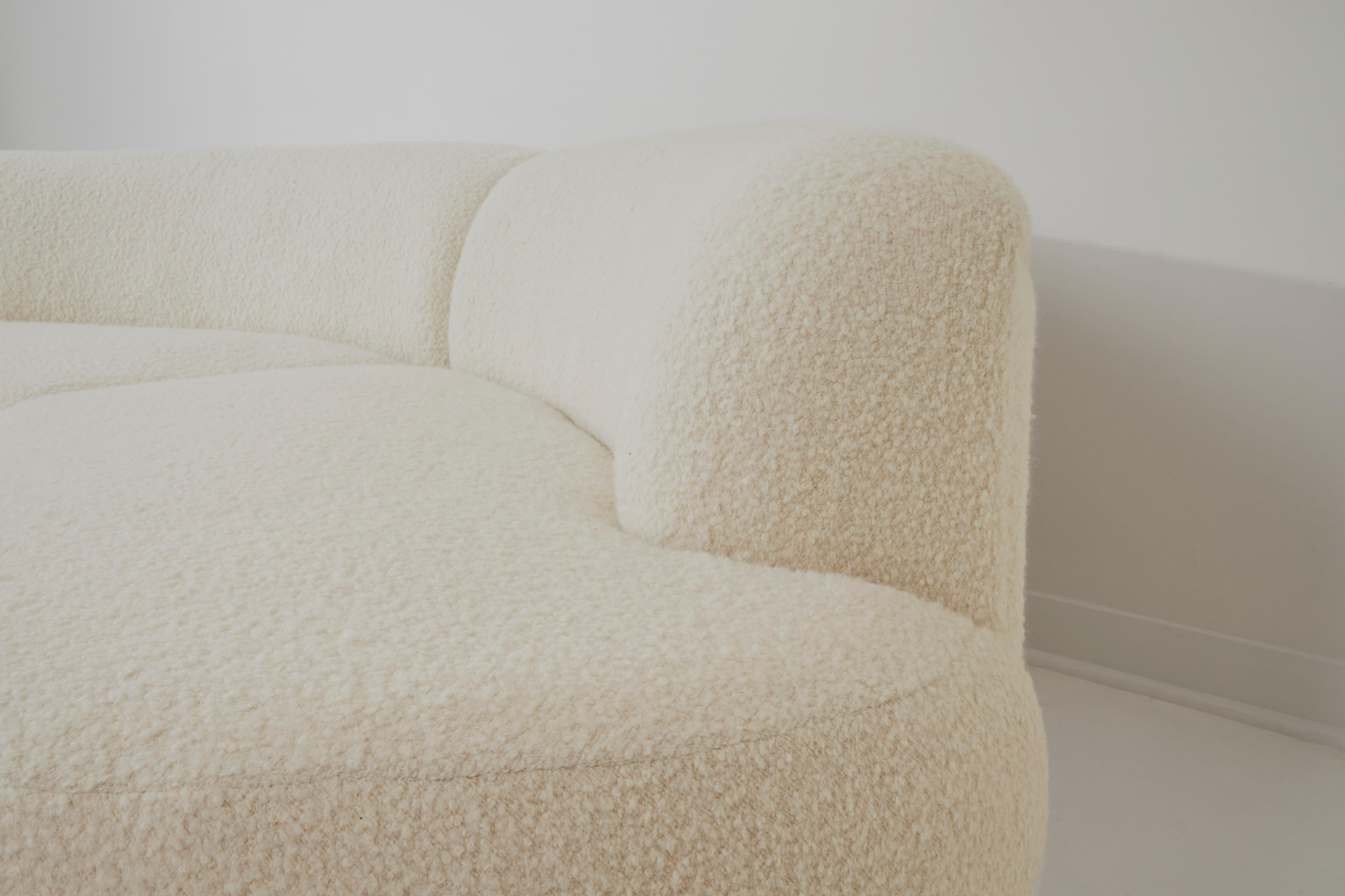 This stunning custom creation, crafted in Paris in 2023, is a three-piece sofa upholstered in white bouclé wool from Pierre Frey's Louison collection. Its curved, dynamic design enhances any space, imparting a comfortable and soft touch to the