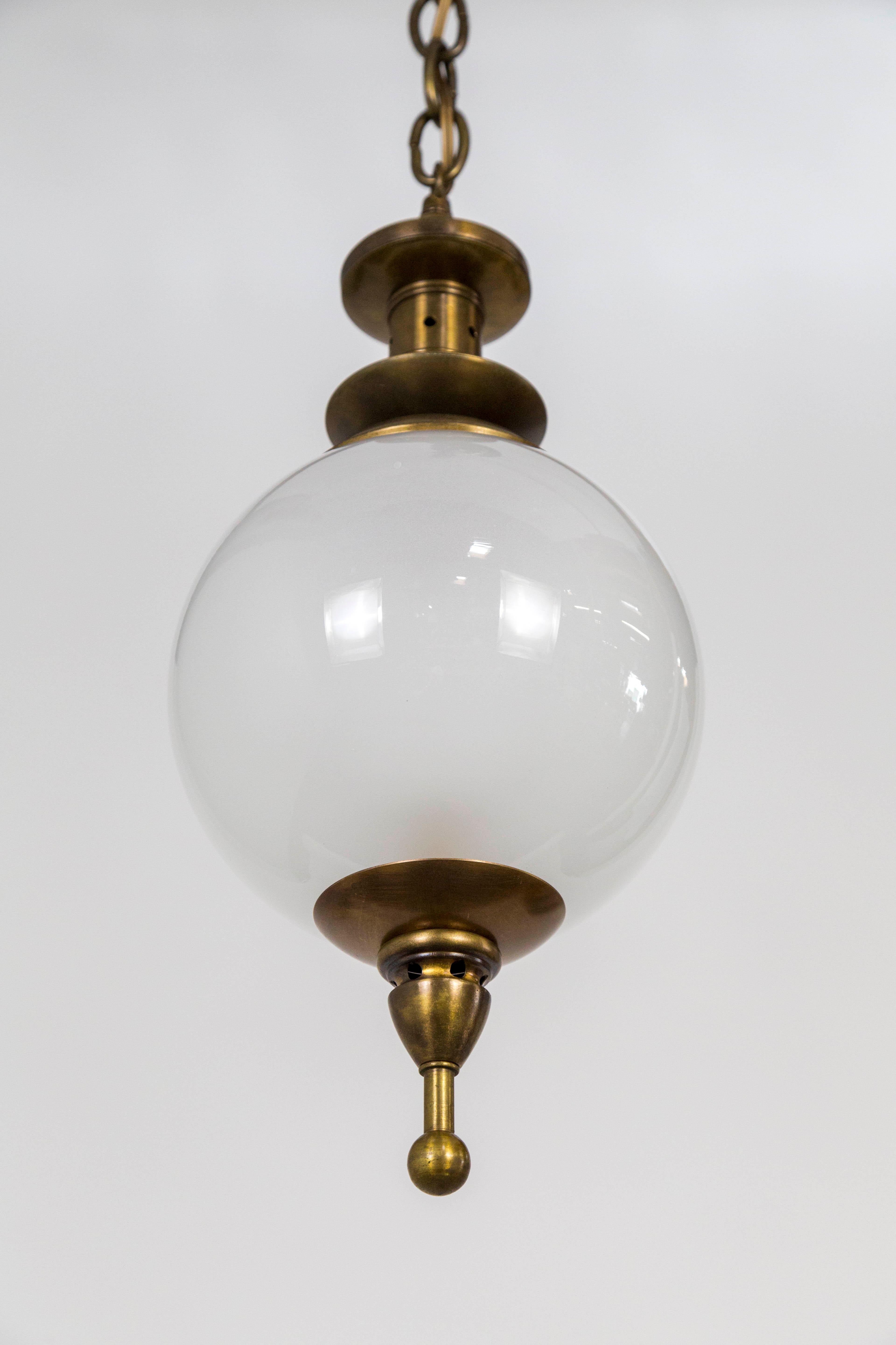 We created two custom, brass capped, hanging glass sphere lights; made with brass parts tinted in oil rubbed bronze, and antique, white, glass globes. Price listed is for one pendant. Measures: 8