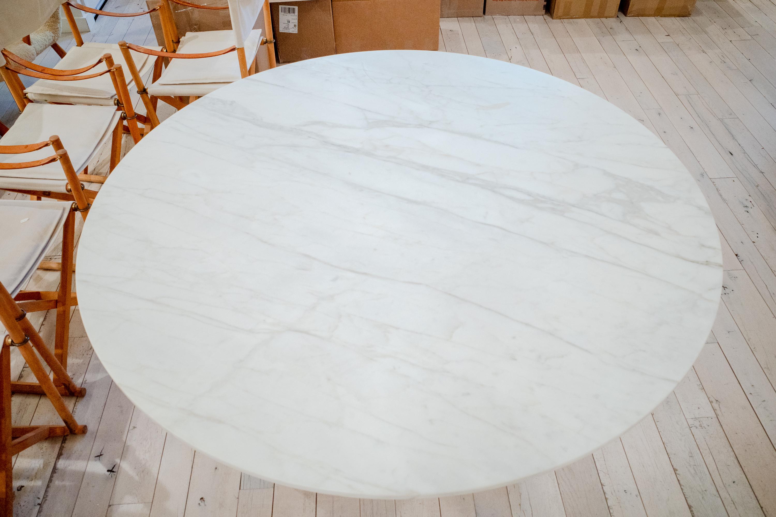 A beautiful round piece of Calacatta marble at five feet wide supported by an eleagent real brass open cube base. 
