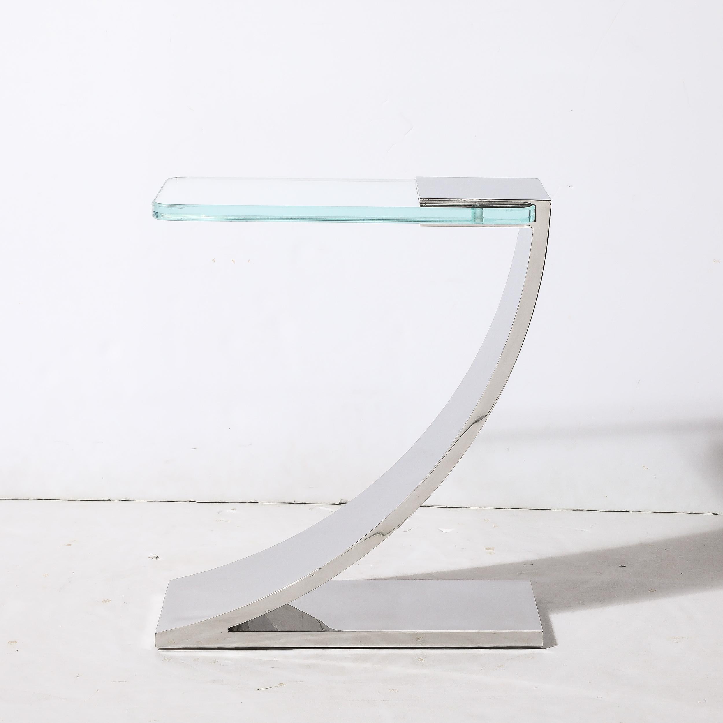 This sleek and sophisticated custom fabricated Modernist Cantilevered Side Table With Transparent Glass Top in Polished Nickel, made for High Style Deco in New York, originates from the United States during the 21st Century. This example is in