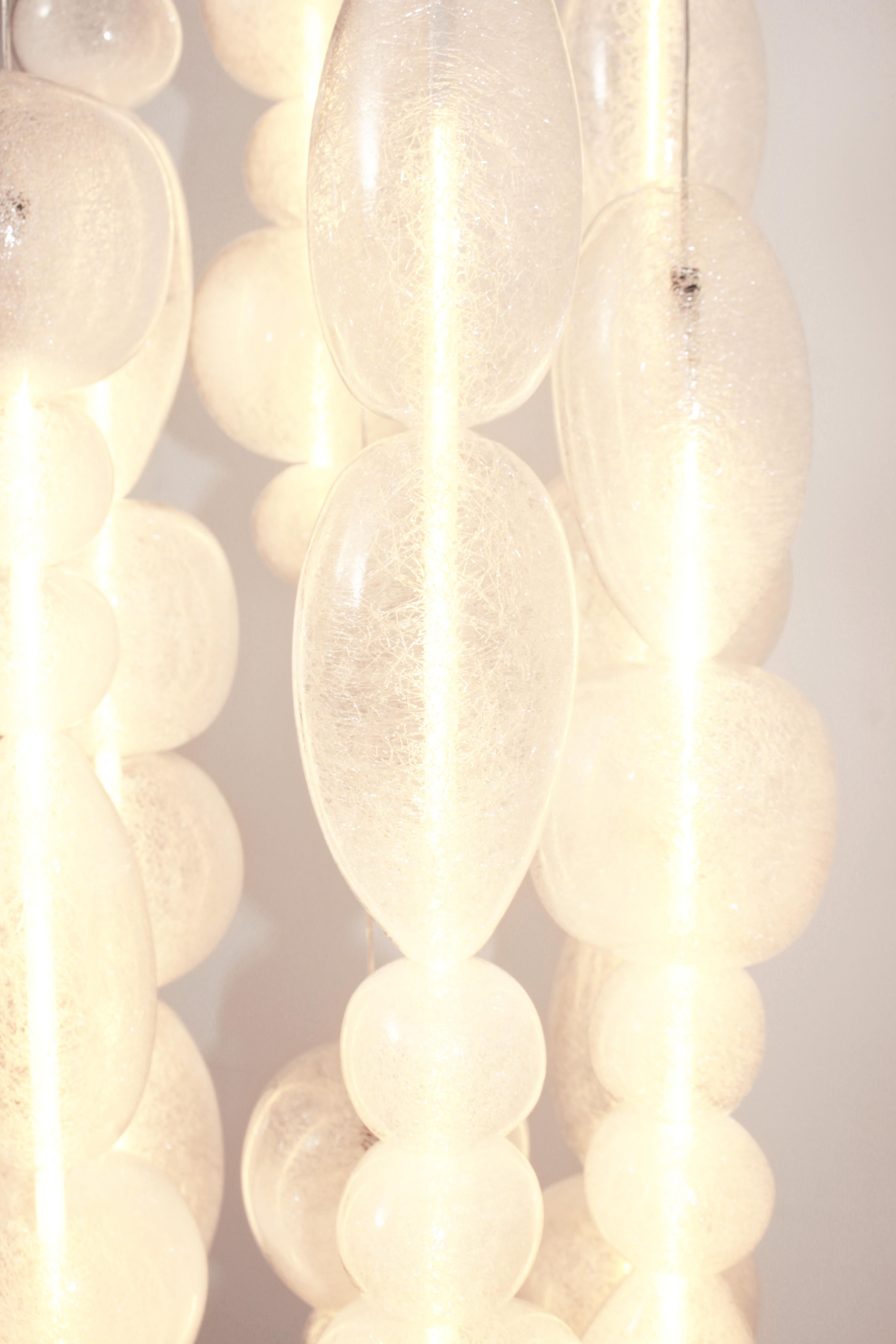 Custom-made mouth-blown transparent glass pendants. 12 glass columns on a 457 mm x 762 mm Matte White canopy.
Dimmable LED Tubes.
Total height of 1900 mm with adjustable cables even once the light is installed.

The Chavana collection features