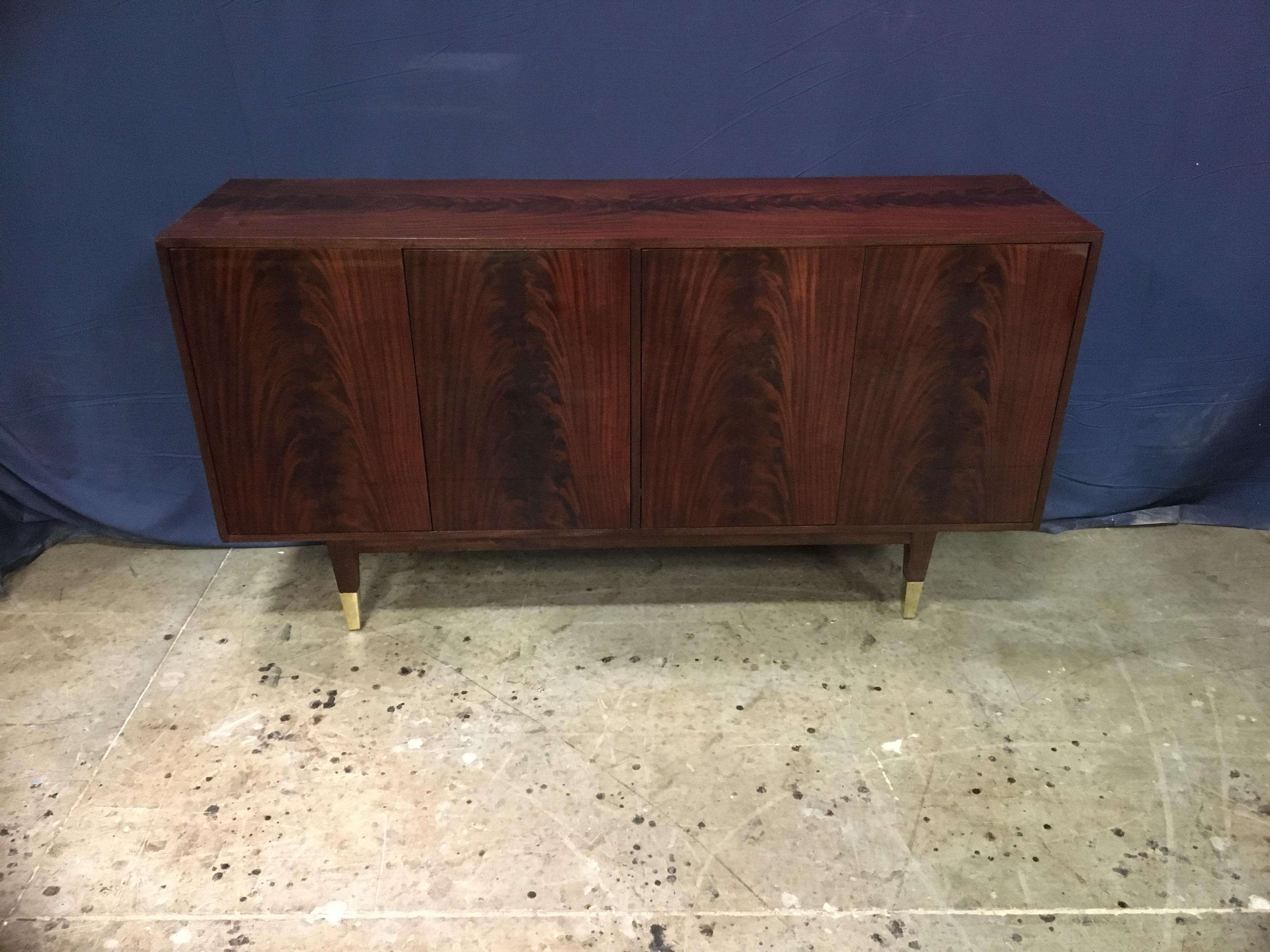 This is made-to-order midcentury style mahogany four door sideboard/credenza made in the Leighton Hall shop. It features four doors with swirly crotch mahogany and a top and sides of matching swirly crotch mahogany. It has square tapered legs which