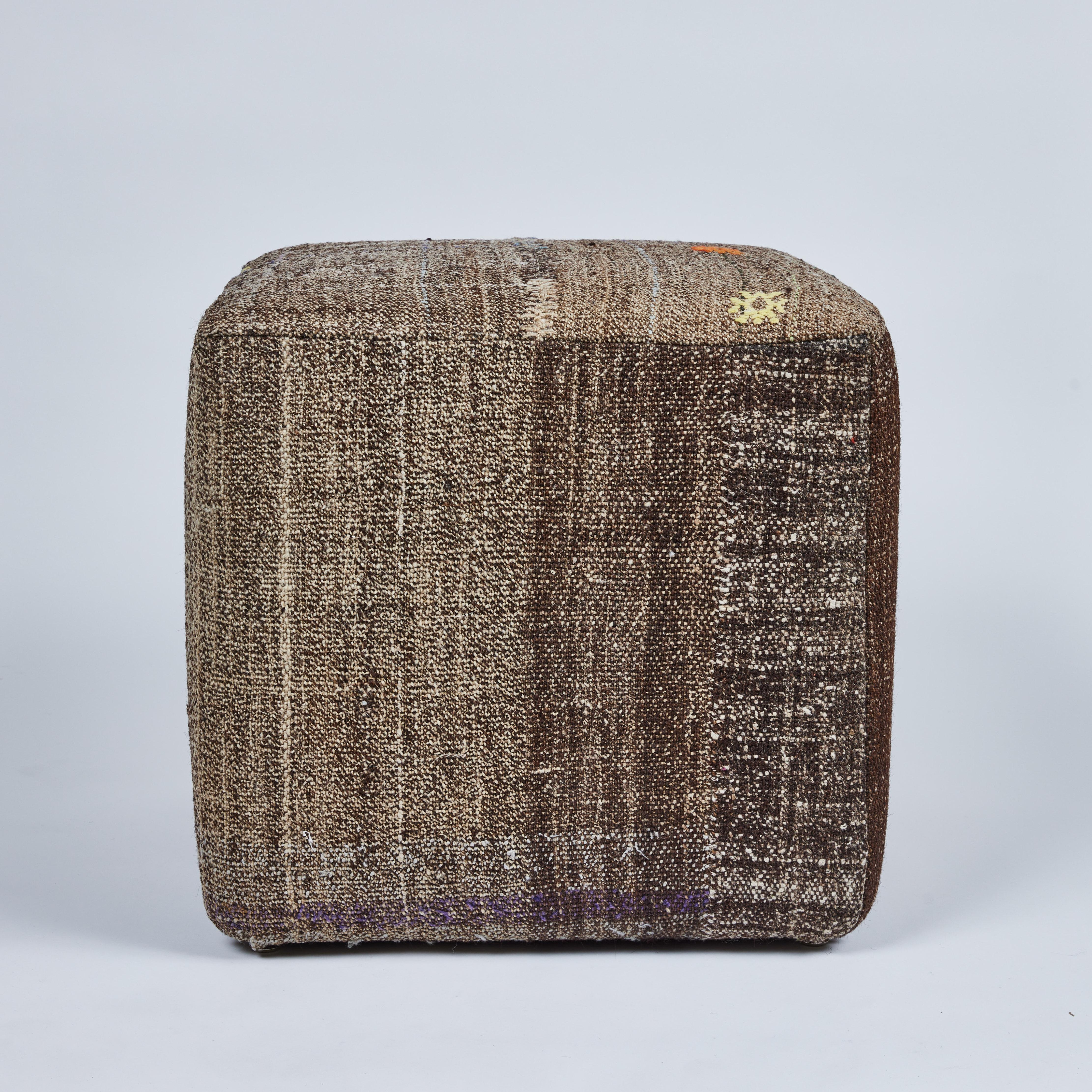 This cool custom cube stool has been upholstered in a handsome vintage wool rug. It is a muted brown and cream patterned base with accent touches of orchid, yellow, orange, green, blue and red stitched and woven throughout the overall pattern. It