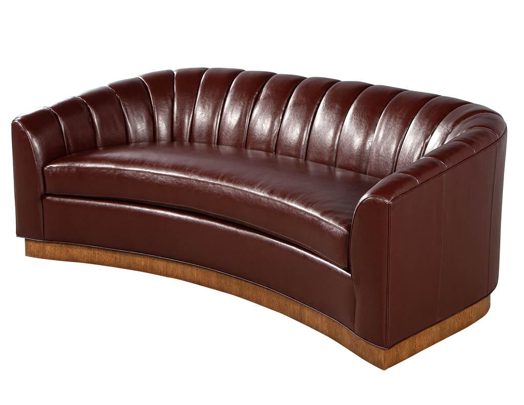 Custom curved channel back sofa by Carrocel. Displayed with a textured light wood platform and luxurious Italian leather material. Featuring unique channel back design with removable seat cushion. Available in custom finishes and fabrics, pricing