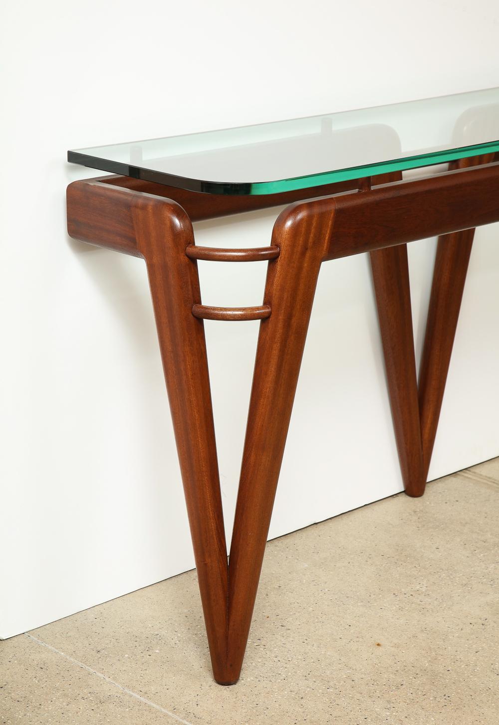 Studio-built mahogany console table that secures itself to the wall. Thick floating glass top with rounded corners.