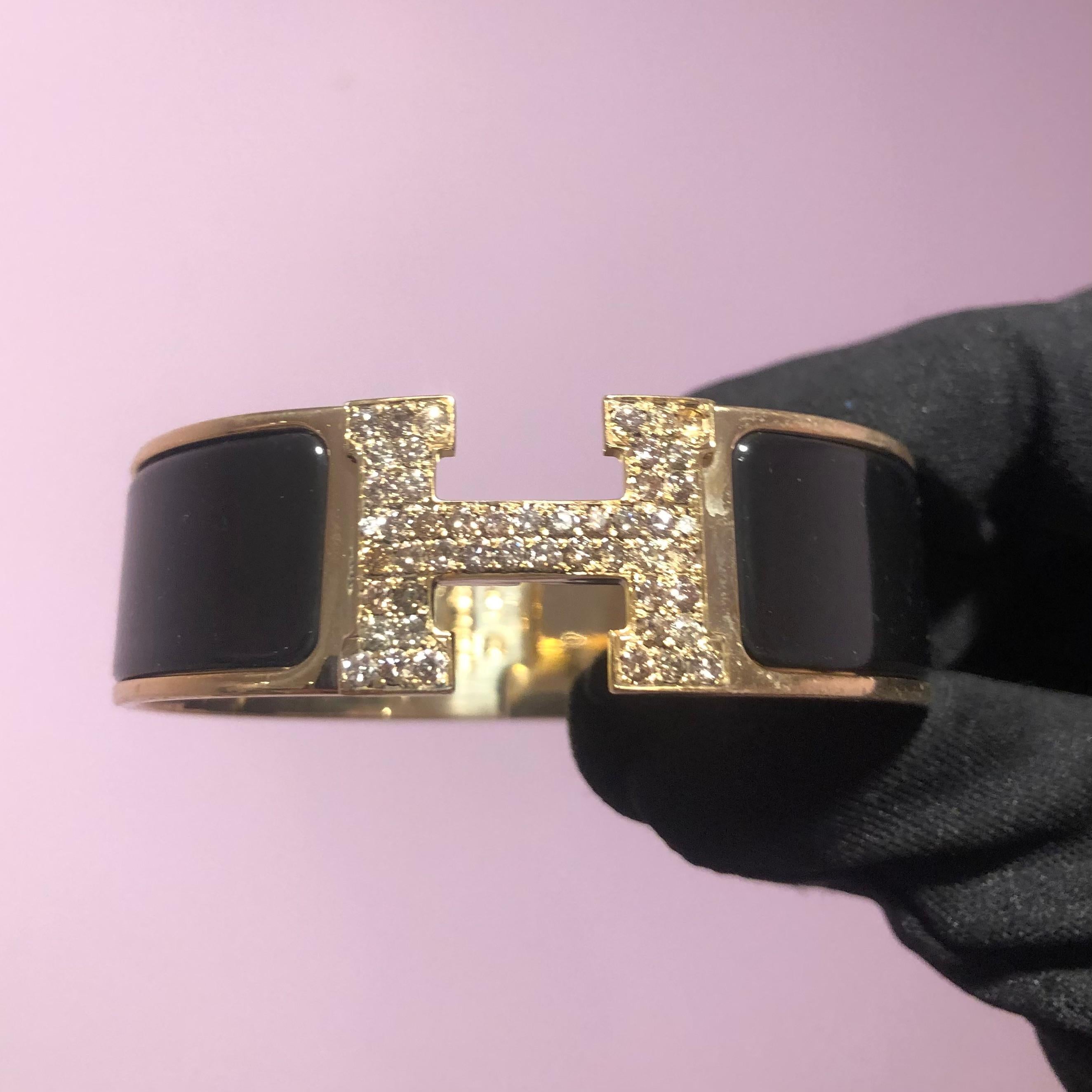 Custom Diamond Hermes Clic Clac H Bracelet complete with original box and booklet papers.

An original Hermes Clic Clac H bracelet GM size in black and gold color is customized hand-set with approx. 2.00 carats of natural genuine earth-mined SI-I