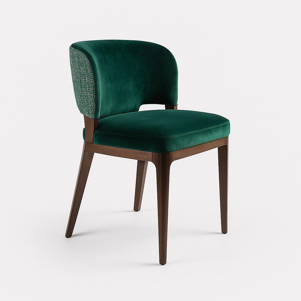 Raffinata sedia da pranzo con schienale dolcemente curvato e una silhouette elegante, rivestita in velluto verde smeraldo. Lo schienale esterno è in contrasto con il tessuto, che aggiunge profondità e interesse tattile. La seduta è generosamente